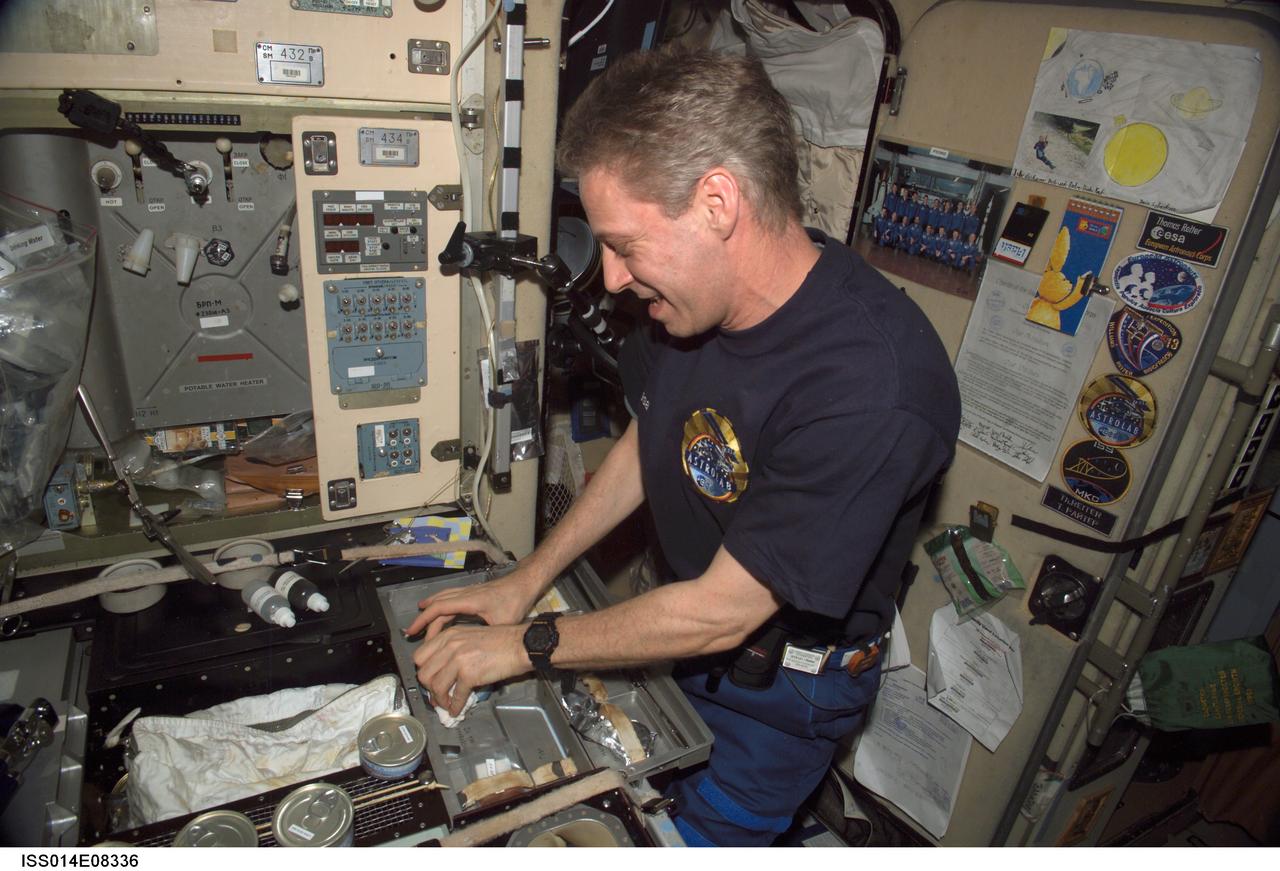 ISS014-E-08336 (27 Nov. 2006) --- European Space Agency (ESA) astronaut Thomas Reiter, Expedition 14 flight engineer, prepares to eat a meal at the galley in the Zvezda Service Module of the International Space Station.