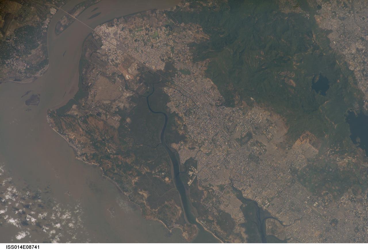 ISS014-E-08741 (28 Nov. 2006) --- Mumbai, India is featured in this image photographed by an Expedition 14 crewmember on the International Space Station. This view is one of three (frames 8741, 8742 and 8744) acquired within ten seconds of each other as the station passed over India. Mumbai (formerly known as Bombay) is a so-called mega city, with over 21 million people living in the greater Mumbai metropolitan region. Mega cities like Tokyo, New York, Sao Paulo, and Mumbai are also known as conurbations -- large contiguous areas of urban land cover formed from the growth and merging together of previously separate and distinct urban centers. The Mumbai conurbation includes several municipal entities including Bhiwandi, Kalyan, Thane, and Ulhasnagar. Located along the coast of western India on Salsette Island, Mumbai is generally considered to be the most modern of India's cities and is a major economic, transportation, and cultural center. Almost cloud-free conditions reveal the continuous urban land cover of the mega city extending north to south across Salsette Island -- a distance of nearly 50 kilometers. Sanjay Gandhi National Park, bordered on three sides by the urbanized area, is the largest national park in the world located within city limits. In addition to providing a refuge for native flora and fauna, the park also includes two lakes that form part of the Mumbai drinking water system.