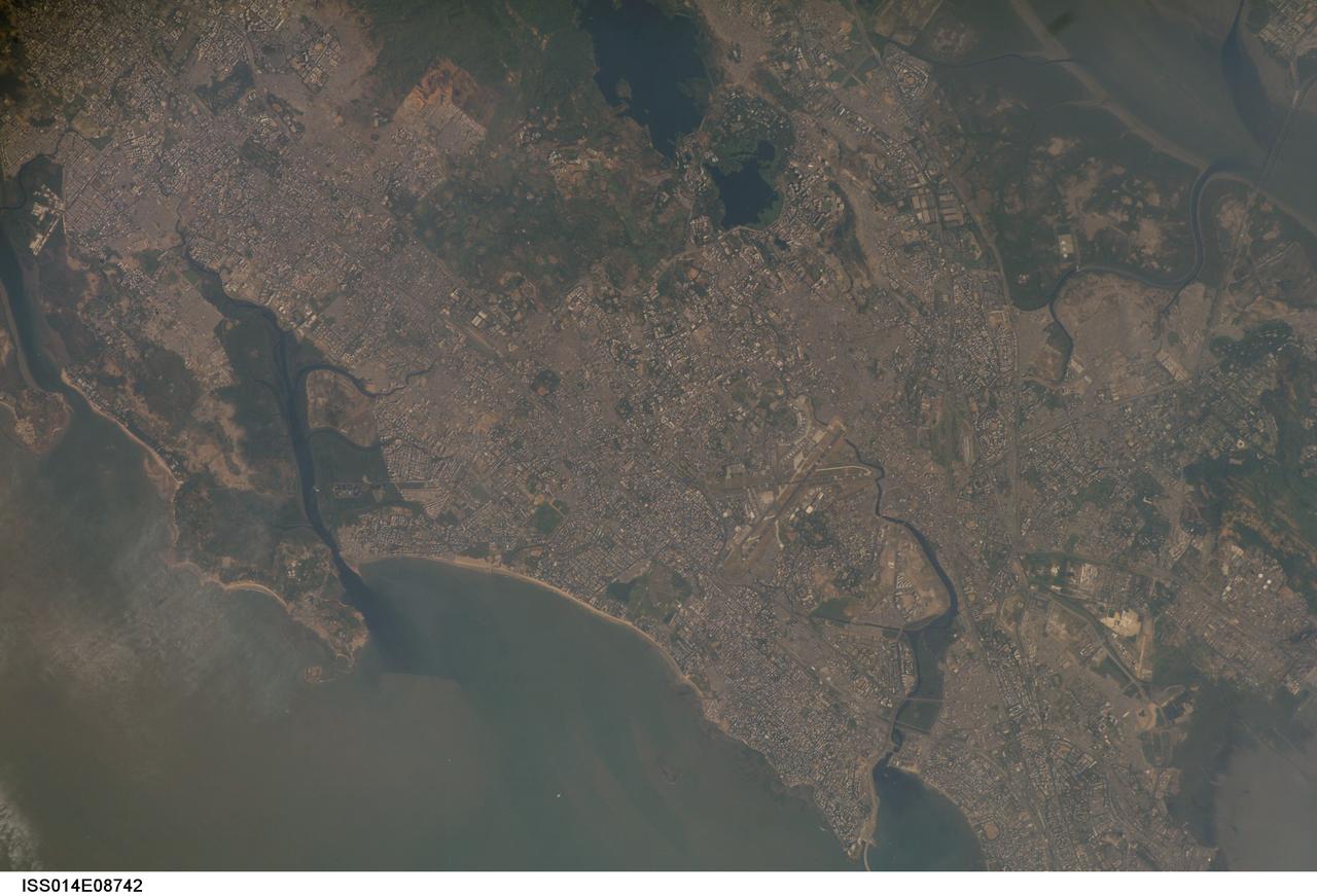 ISS014-E-08742 (28 Nov. 2006) --- Mumbai, India is featured in this image photographed by an Expedition 14 crewmember on the International Space Station. This view is one of three (frames 8741, 8742 and 8744) acquired within ten seconds of each other as the station passed over India. Mumbai (formerly known as Bombay) is a so-called mega city, with over 21 million people living in the greater Mumbai metropolitan region. Mega cities like Tokyo, New York, Sao Paulo, and Mumbai are also known as conurbations -- large contiguous areas of urban land cover formed from the growth and merging together of previously separate and distinct urban centers. The Mumbai conurbation includes several municipal entities including Bhiwandi, Kalyan, Thane, and Ulhasnagar. Located along the coast of western India on Salsette Island, Mumbai is generally considered to be the most modern of India's cities and is a major economic, transportation, and cultural center. Almost cloud-free conditions reveal the continuous urban land cover of the mega city extending north to south across Salsette Island -- a distance of nearly 50 kilometers. Sanjay Gandhi National Park (partially out of frame), bordered on three sides by the urbanized area, is the largest national park in the world located within city limits. In addition to providing a refuge for native flora and fauna, the park also includes two lakes that form part of the Mumbai drinking water system.