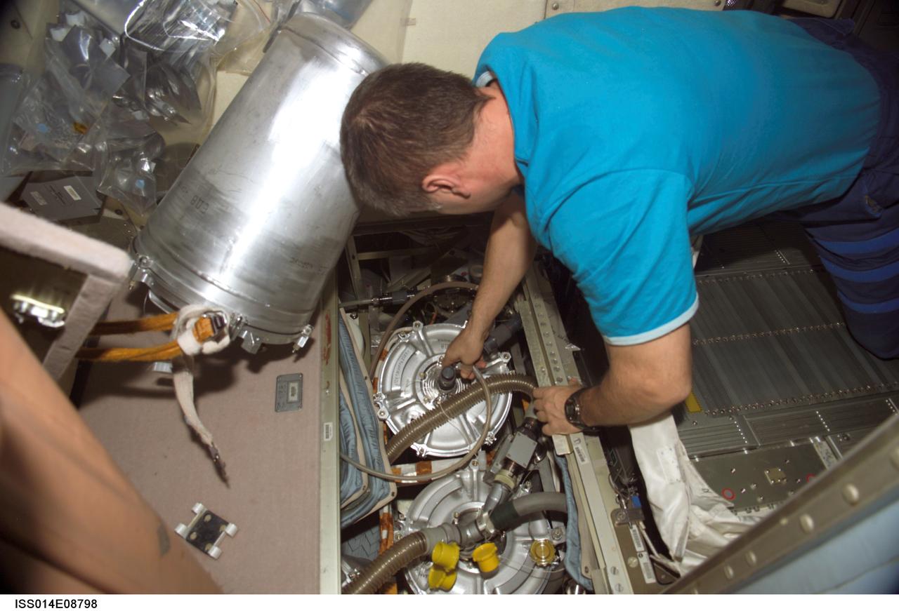 ISS014-E-08798 (29 Nov. 2006) --- Cosmonaut Mikhail Tyurin, Expedition 14 flight engineer, replaces the E-K pre-treat container and hose in the waste management system in the Zvezda Service Module of the International Space Station.