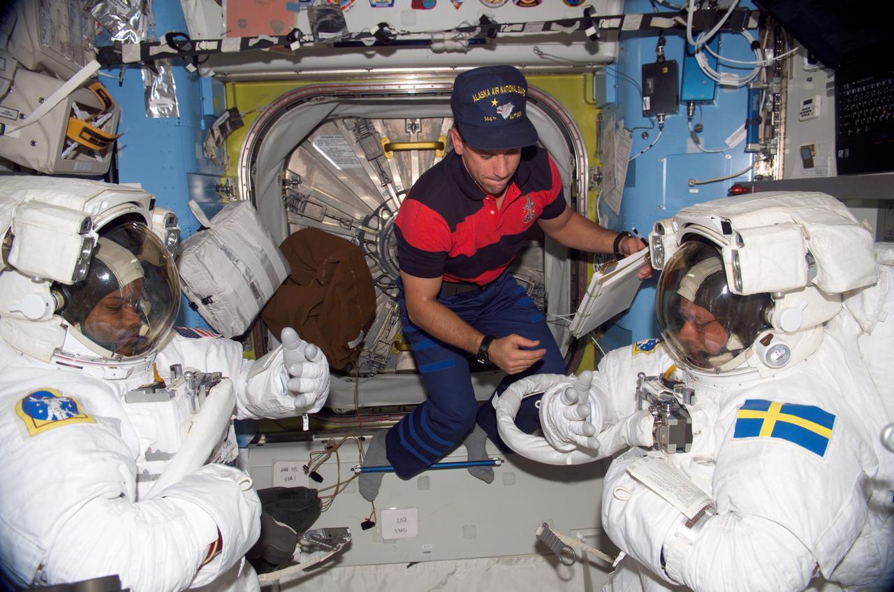 ISS014-E-09608 (12 Dec. 2006) --- Attired in their extravehicular mobility unit (EMU) spacesuits, astronaut Robert L. Curbeam, Jr. (left) and European Space Agency (ESA) astronaut Christer Fuglesang, both STS-116 mission specialists, prepare for the mission's first session of extravehicular activity (EVA) in the Quest Airlock of the International Space Station while Space Shuttle Discovery was docked with the station. Astronaut William A. (Bill) Oefelein (center), pilot, assisted Curbeam.