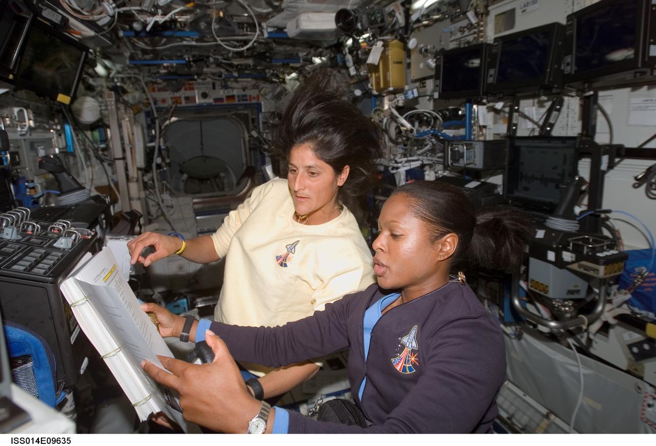 ISS014-E-09635 (12 Dec. 2006) --- Astronauts Joan E. Higginbotham (foreground), STS-116 mission specialist, and Sunita L. Williams, Expedition 14 flight engineer, refer to a procedures checklist as they work the controls of the Space Station Remote Manipulator System (SSRMS) or Canadarm2 in the Destiny laboratory of the International Space Station during flight day four activities.
