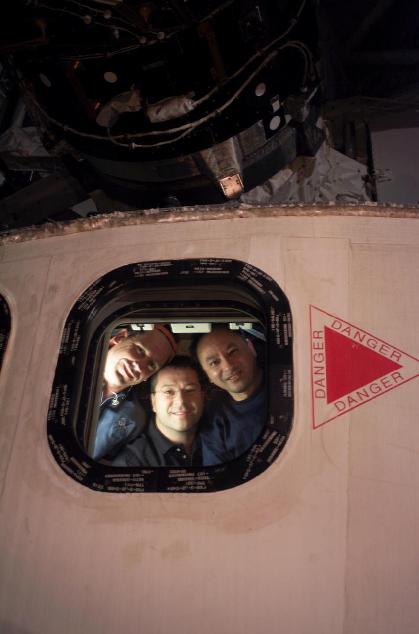 ISS014-E-09804 (14 Dec. 2006) --- From the aft flight deck on Space Shuttle Discovery, astronauts William A. (Bill) Oefelein (left), STS-116 pilot; Nicholas J. M. Patrick, mission specialist; and Mark L. Polansky, commander, look through an overhead window toward their spacewalking crewmembers, who captured the image during the mission's second of three planned sessions of extravehicular activity (EVA).