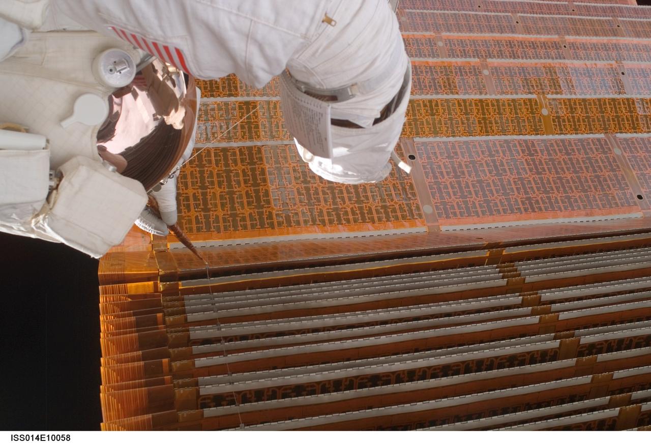 ISS014-E-10058 (18 Dec. 2006) --- Astronaut Robert L. Curbeam Jr., STS-116 mission specialist, works with the port overhead solar array wing on the International Space Station's P6 truss during the mission's fourth session of extravehicular activity (EVA). European Space Agency (ESA) astronaut Christer Fuglesang (out of frame), mission specialist, worked in tandem with Curbeam, using specially prepared, tape-insulated tools, to guide the array wing neatly inside its blanket box during the 6-hour, 38-minute spacewalk.