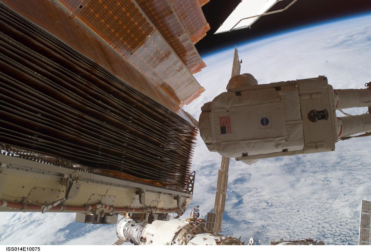 ISS014-E-10075 (18 Dec. 2006) --- Astronaut Robert L. Curbeam Jr., STS-116 mission specialist, works with the port overhead solar array wing on the International Space Station's P6 truss during the mission's fourth session of extravehicular activity (EVA). European Space Agency (ESA) astronaut Christer Fuglesang (out of frame), mission specialist, worked in tandem with Curbeam, using specially prepared, tape-insulated tools, to guide the array wing neatly inside its blanket box during the 6-hour, 38-minute spacewalk.