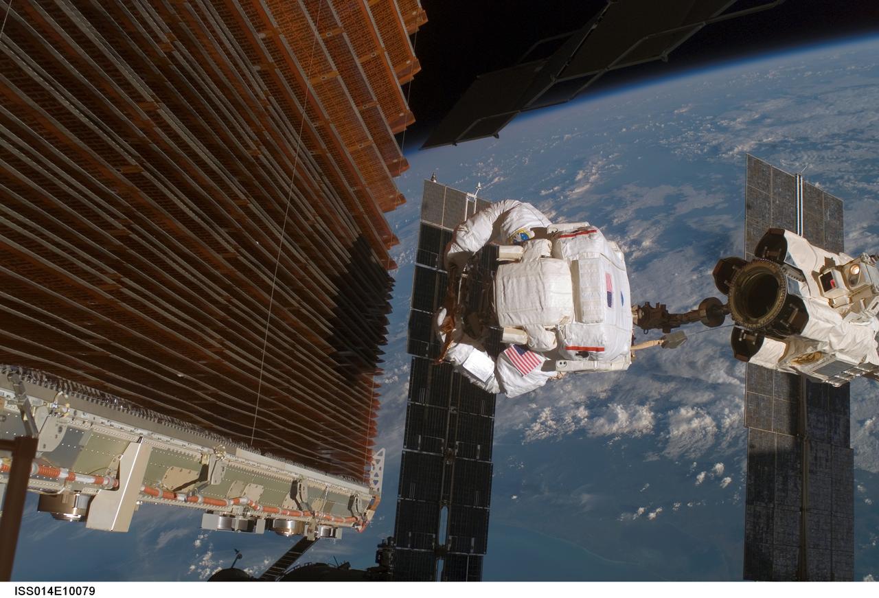 ISS014-E-10079 (18 Dec. 2006) --- Astronaut Robert L. Curbeam Jr., STS-116 mission specialist, works with the port overhead solar array wing on the International Space Station's P6 truss during the mission's fourth session of extravehicular activity (EVA). European Space Agency (ESA) astronaut Christer Fuglesang (out of frame), mission specialist, worked in tandem with Curbeam, using specially prepared, tape-insulated tools, to guide the array wing neatly inside its blanket box during the 6-hour, 38-minute spacewalk.