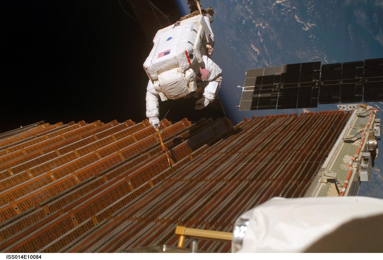 ISS014-E-10084 (18 Dec. 2006) --- Astronaut Robert L. Curbeam Jr., STS-116 mission specialist, works with the port overhead solar array wing on the International Space Station's P6 truss during the mission's fourth session of extravehicular activity (EVA). European Space Agency (ESA) astronaut Christer Fuglesang (out of frame), mission specialist, worked in tandem with Curbeam, using specially prepared, tape-insulated tools, to guide the array wing neatly inside its blanket box during the 6-hour, 38-minute spacewalk.