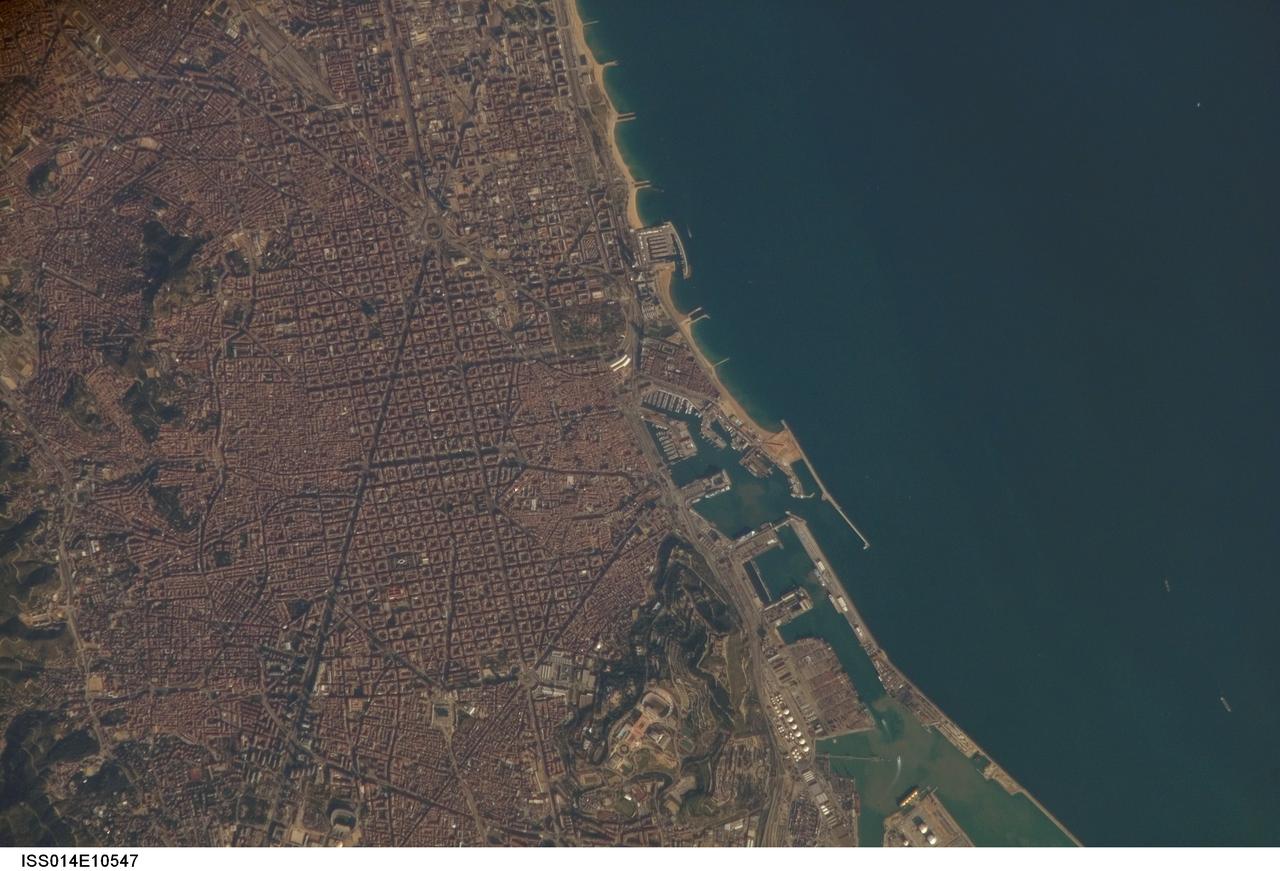 ISS014-E-10547 (30 Dec. 2006) --- Barcelona, Spain is featured in this image photographed by an Expedition 14 crewmember on the International Space Station. Barcelona occupies a low plateau along the Mediterranean coastal plain. The city is the second largest in Spain (after the capital of Madrid), and hosts the country's largest seaport (portions of which are visible at lower right). This detailed view captures several notable features of the Barcelona urban landscape. The architectural design of the Eixample district (center) displays a grid pattern distinctive for Barcelona. Built during the 19th and 20th centuries, the district was built with octagonal city blocks -- originally intended to be open structures of only two or three sides surrounding gardens and open space. While the original street grid pattern remains, today many of the octagonal blocks are completely built up. The adjacent Cuitat Vella, or old city, presents a much denser building pattern which dates from Roman times. Also visible at lower right is the 173-meter high Montjuic Mountain -- historically the location of fortresses due to its strategic position overlooking the city's harbor. Light tan and orange structures visible at the crest of the mountain include the stadium and other buildings used in the 1992 Summer Olympic Games at Barcelona.