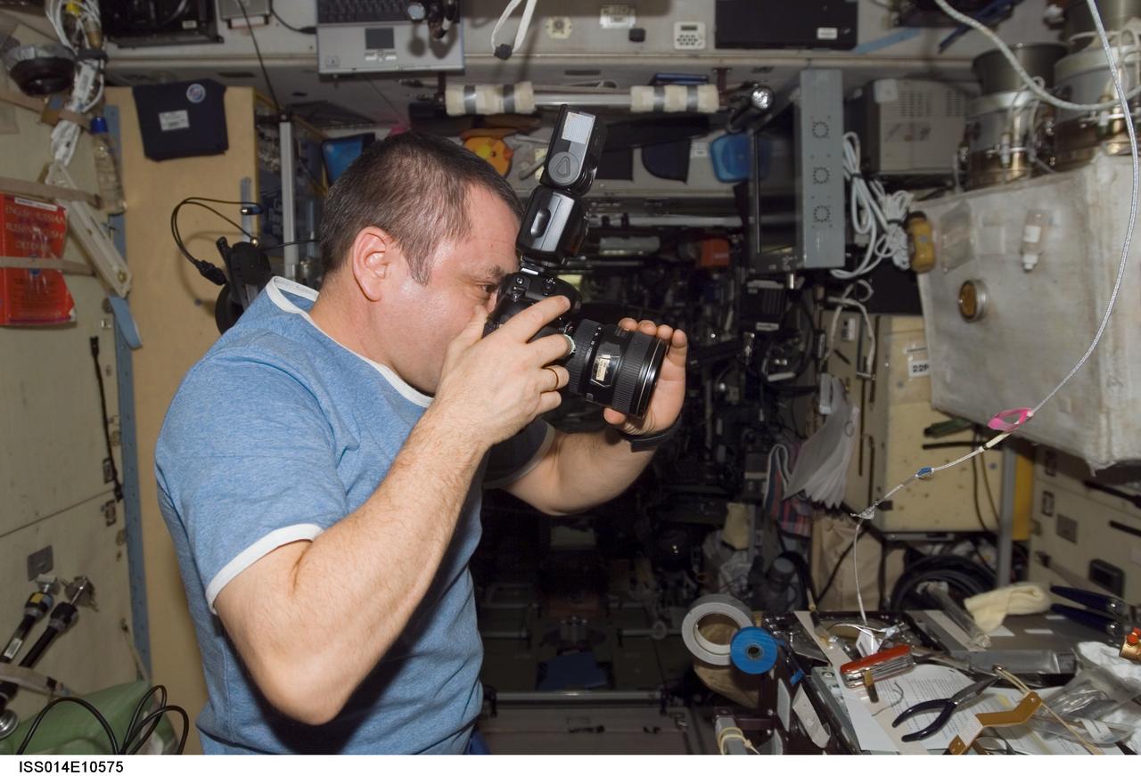 ISS014-E-10575 (28 Dec. 2006) --- Cosmonaut Mikhail Tyurin, Expedition 14 flight engineer representing Russia's Federal Space Agency, using a digital still photo camera, documents repair work done on a frayed cable in the Zvezda Service Module of the International Space Station.