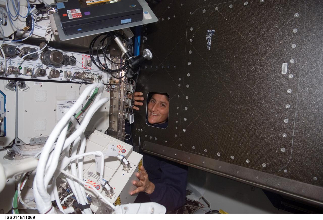 ISS014-E-11069 (3 Jan. 2007) --- Astronaut Sunita L. Williams, Expedition 14 flight engineer, looks through an opening during the Oxygen Generator System (OGS) rack rotation in the Destiny laboratory of the International Space Station.