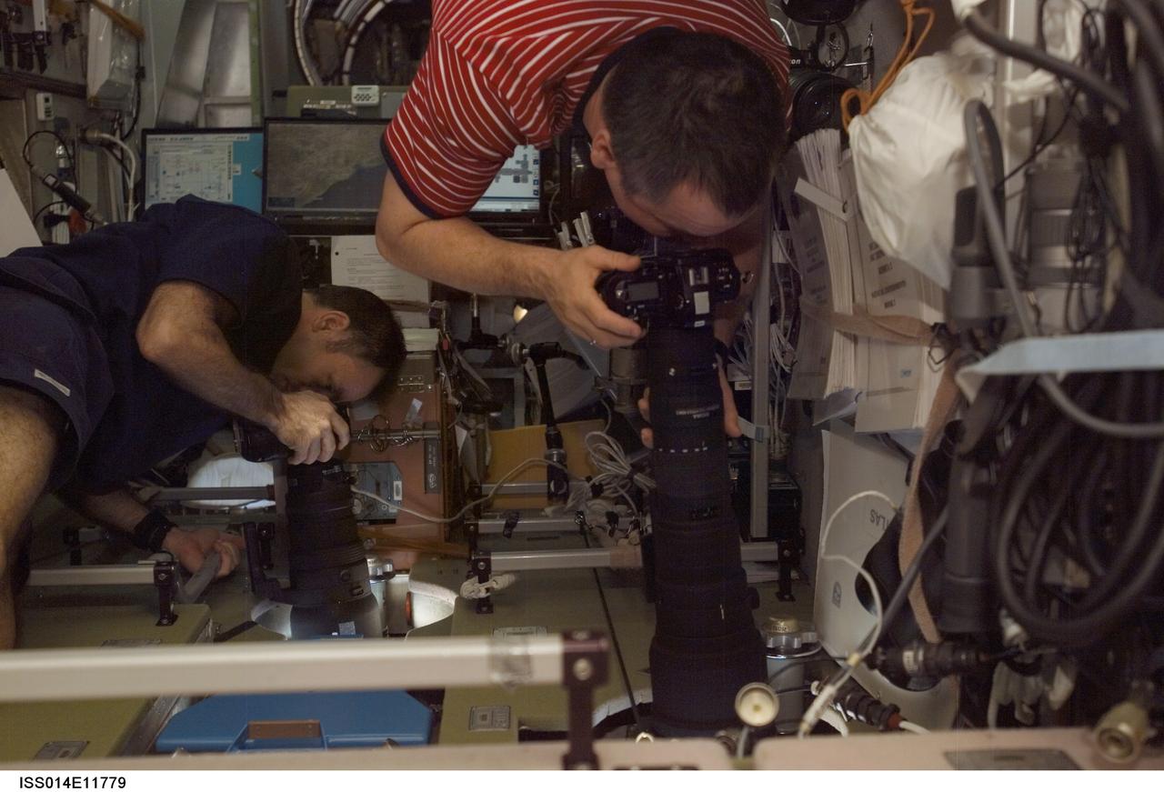 ISS014-E-11779 (12 Jan. 2007) --- Astronaut Michael E. Lopez-Alegria (left), Expedition 14 commander and NASA space station science officer, and cosmonaut Mikhail Tyurin, flight engineer representing Russia's Federal Space Agency, use still cameras at windows in the Zvezda Service Module of the International Space Station.