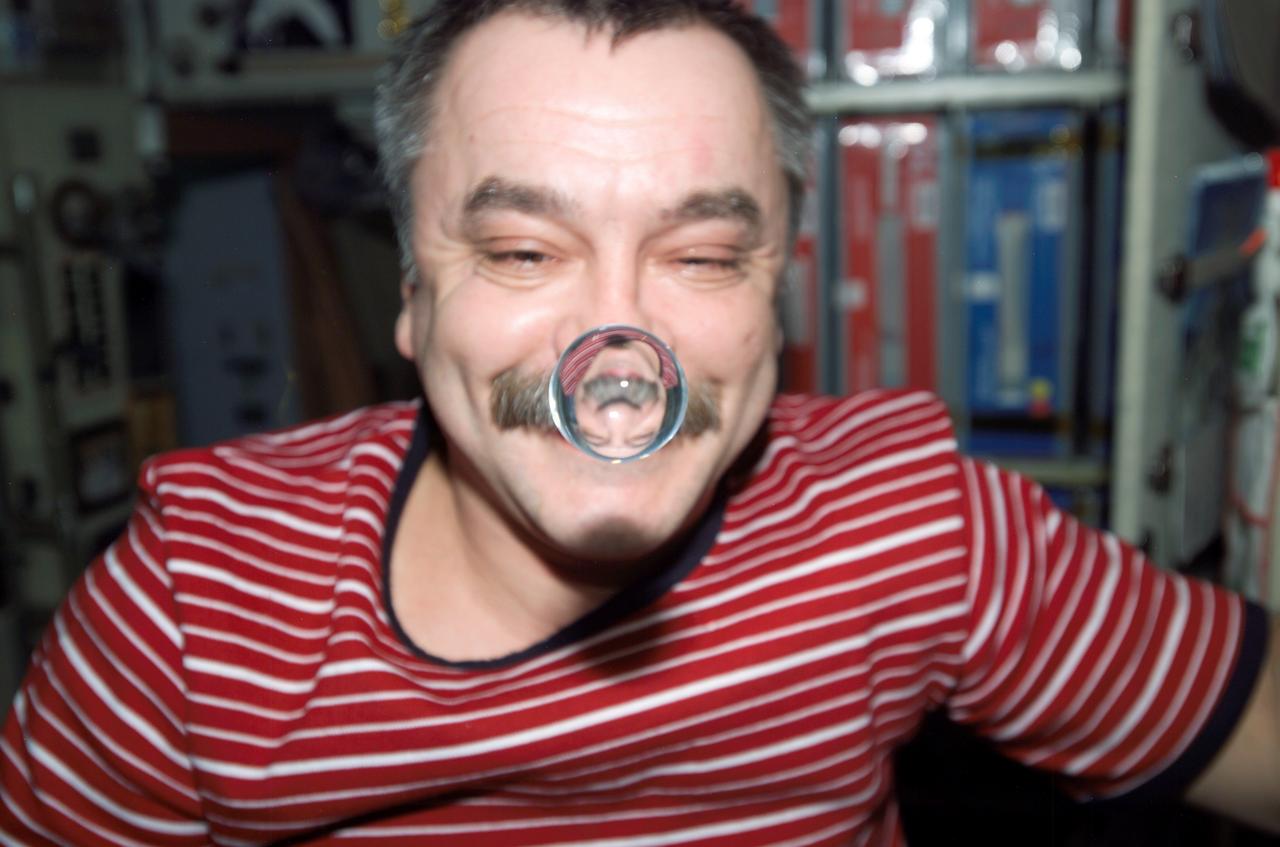 ISS014-E-11798 (14 Jan. 2007) --- Cosmonaut Mikhail Tyurin, Expedition 14 flight engineer representing Russia's Federal Space Agency, watches a water bubble float between him and the camera, showing his image refracted, in the Zvezda Service Module of the International Space Station.