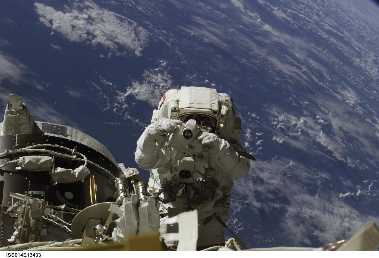 ISS014-E-13433 (8 Feb. 2007) --- Astronaut Michael E. Lopez-Alegria, Expedition 14 commander and NASA space station science officer, uses a digital still camera during the final of three sessions of extravehicular activity (EVA) in nine days, as construction continues on the International Space Station. During the 6-hour, 40-minute spacewalk, Lopez-Alegria and Sunita L. Williams (out of frame), flight engineer, completed tasks that will allow for the attachment of a cargo platform during the STS-118 mission this summer and relocation of the P6 truss during STS-120 later this year.  A blue and white Earth provides the backdrop for the image.