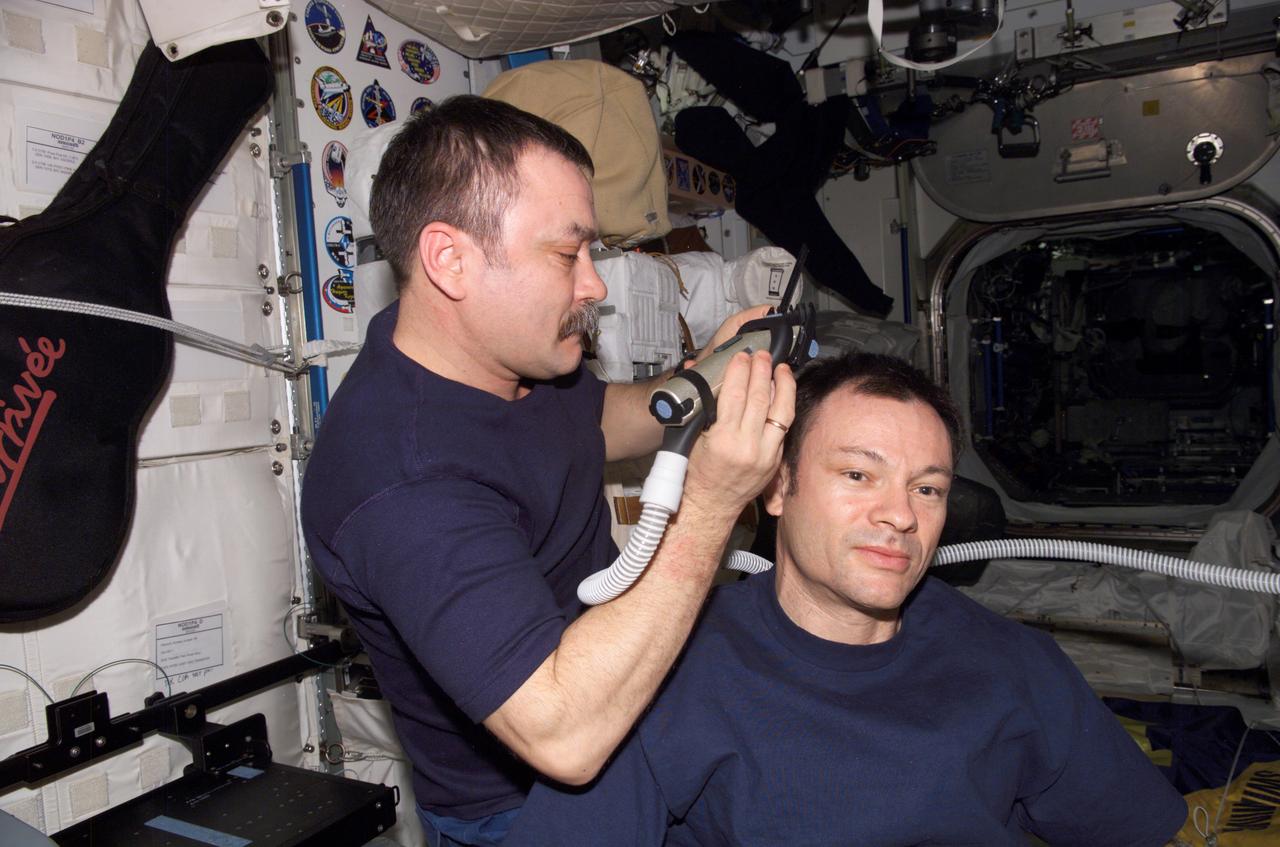 ISS014-E-14031 (20 Feb. 2007) --- Cosmonaut Mikhail Tyurin, Expedition 14 flight engineer representing Russia's Federal Space Agency, trims commander Michael E. Lopez-Alegria's hair in the Unity node of the International Space Station. Tyurin used hair clippers fashioned with a vacuum device to garner freshly cut hair.