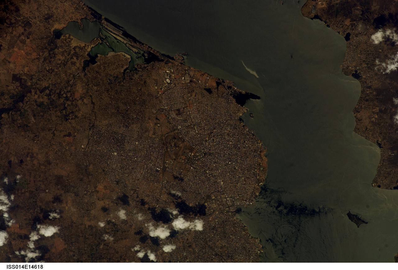 ISS014-E-14618 (23 Feb. 2007) --- Maracaibo City and Oil Slick, Venezuela are featured in this image photographed by an Expedition 14 crewmember on the International Space Station. This view depicts the narrow (6 kilometers) strait between Lake Maracaibo to the south and the Gulf of Venezuela to the north. This brackish lake in northern Venezuela is the largest in South America. The lake and its small basin are situated atop a vast reservoir of buried oil deposits, first tapped in 1914. Venezuela is now the world's fifth largest oil producer. The narrow strait is deepened to allow access by ocean-going vessels, dozens of which now daily transport approximately 80 per cent of Venezuela's oil to world markets. Shipping is one of the main polluters of the lake, caused by the dumping of ballast and other waste. An oil slick, likely related to bilge pumping, can be seen as a bright streak northeast of El Triunfo. Other sources of pollution to the lake include underwater oil pipeline leakage, untreated municipal and industrial waste from coastal cities, and runoff of chemicals from surrounding farm land. Deepening the narrow channel for shipping has also allowed saltwater intrusion into the lake, leading to adverse effects to Lake Biota. Since the discovery of oil, cities like Maracaibo have sprung up along the northwestern coastline of the lake. With satellite cities such as San Luis and El Triunfo, greater Maracaibo has a population of approximately 2.5 million. Just outside the lower margin of the picture a major bridge spans the narrows pictured here, connecting cities such as Altagracia (top right) to Maracaibo.
