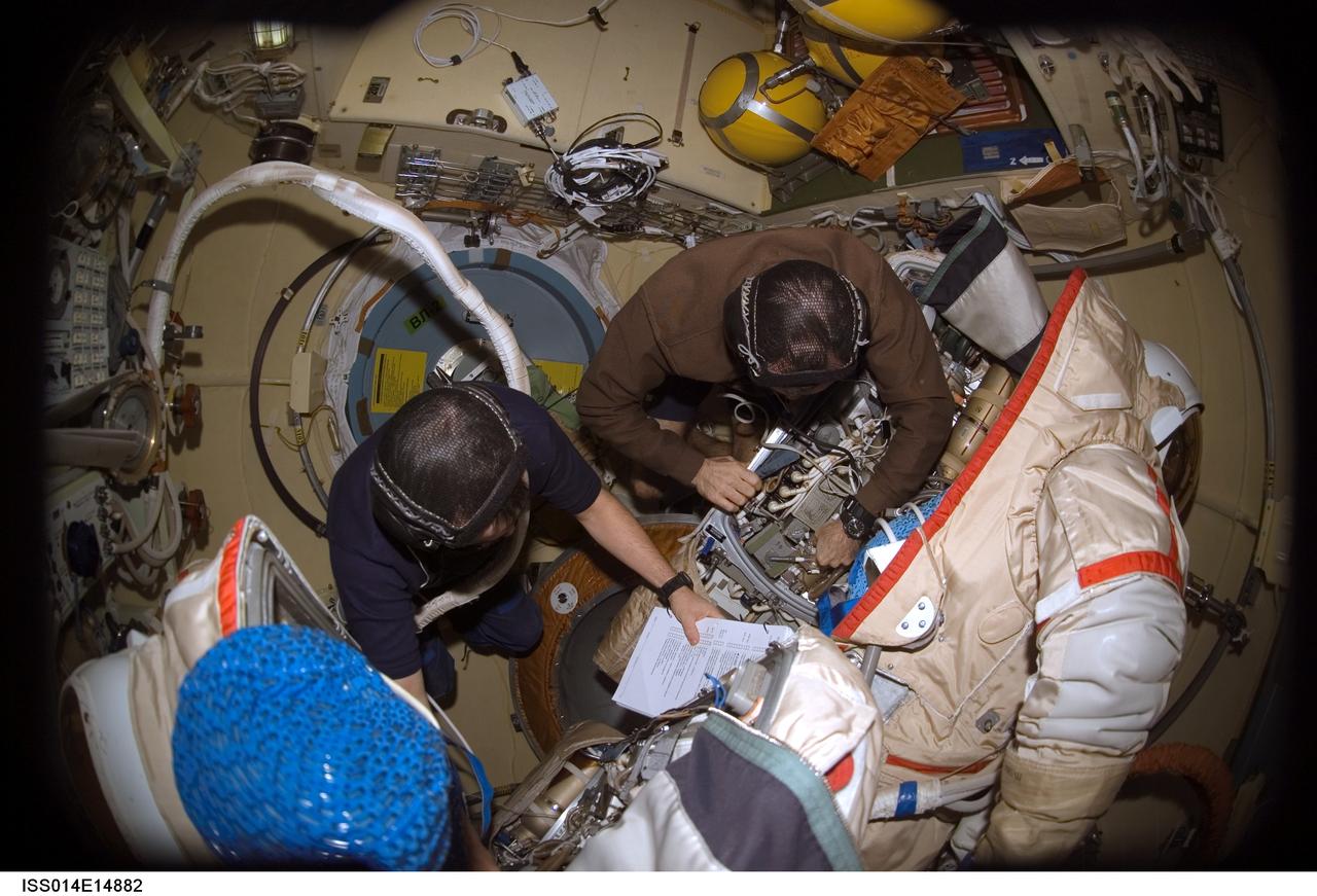 ISS014-E-14882 (21 Feb. 2007) --- Astronaut Michael E. Lopez-Alegria (right), Expedition 14 commander and NASA space station science officer; and cosmonaut Mikhail Tyurin, flight engineer representing Russia's Federal Space Agency, work with a Russian Orlan spacesuit in the Pirs Docking Compartment of the International Space Station.