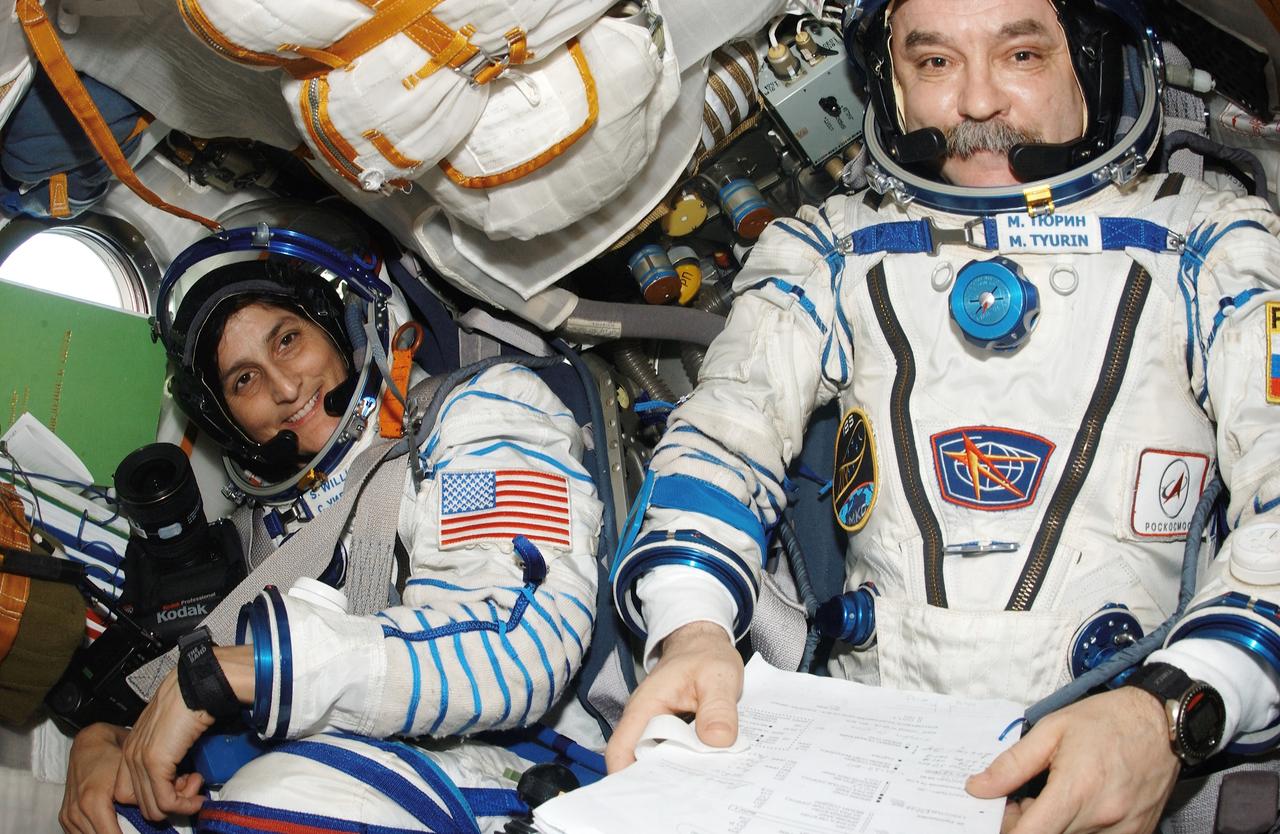 ISS014-E-18764 (29 March 2007) --- Astronaut Sunita L. Williams (left), Expedition 14 flight engineer, and cosmonaut Mikhail Tyurin, Soyuz commander and flight engineer, occupy their seats in the Soyuz 13 (TMA-9) spacecraft docked to the International Space Station. Attired in their Russian Sokol launch and entry suits, Tyurin, Williams and astronaut Michael E. Lopez-Alegria (out of frame), commander and NASA space station science officer, were about to relocate the Soyuz from the Zarya Module nadir port to the Zvezda Service Module aft port in preparation for the arrival of Expedition 15.