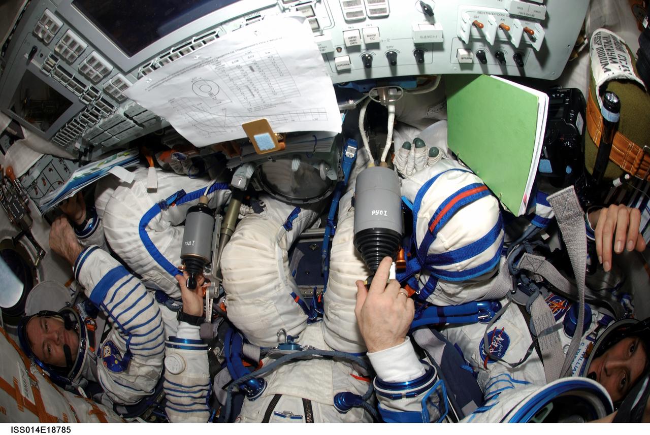 ISS014-E-18785 (29 March 2007) --- Attired in their Russian Sokol launch and entry suits, astronaut Michael E. Lopez-Alegria (left), Expedition 14 commander and NASA space station science officer; cosmonaut Mikhail Tyurin (partially out of frame), Soyuz commander and flight engineer; and astronaut Sunita L. Williams, flight engineer, relocate the Soyuz 13 (TMA-9) spacecraft from the Zarya Module nadir port to the Zvezda Service Module aft port of the International Space Station in preparation for the arrival of Expedition 15.