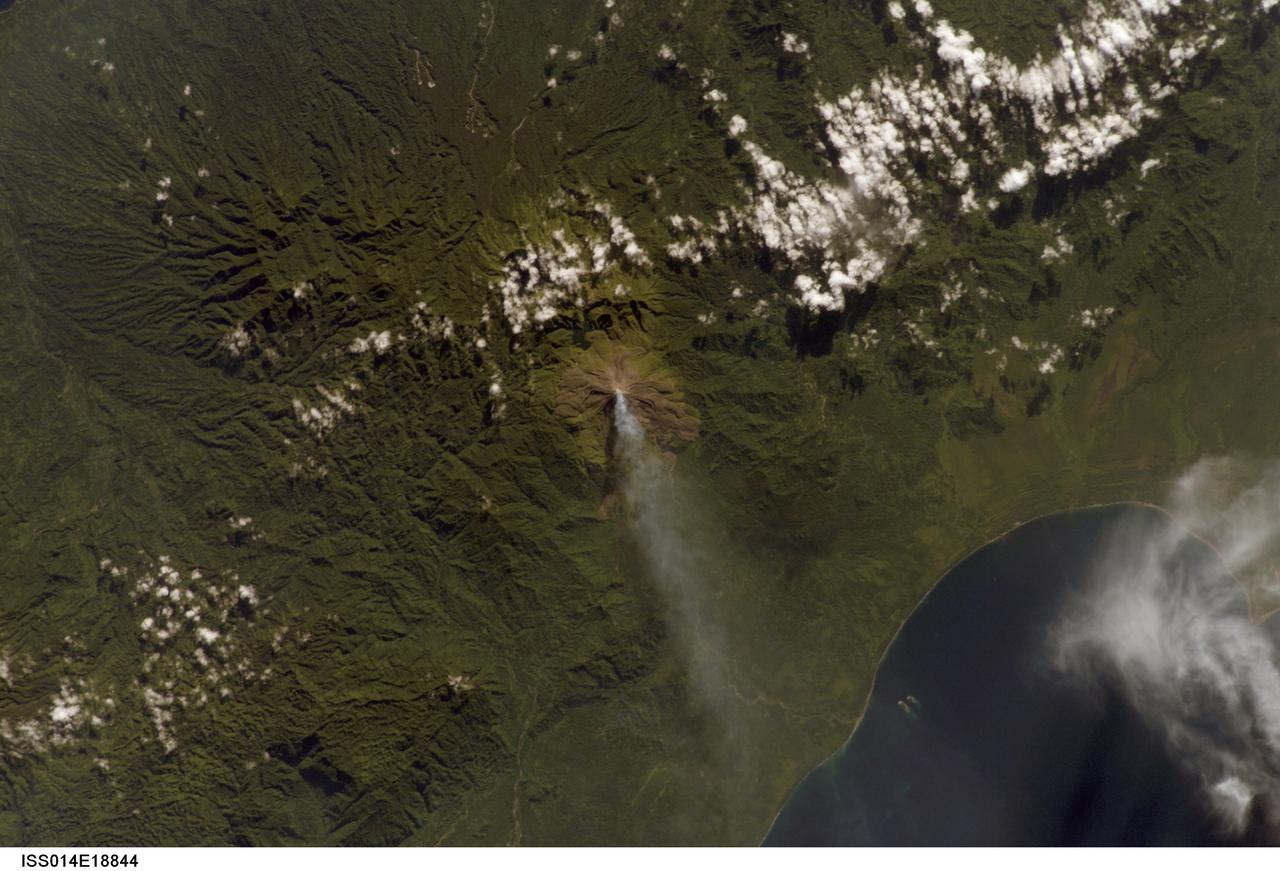 ISS014-E-18844 (2 April 2007) --- A plume at Mt. Bagana, Bougainville Island is featured in this image photographed by an Expedition 14 crewmember on the International Space Station. Bougainville Island, part of the Solomon Islands chain to the east of Papua New Guinea, is typical of many Pacific Rim islands in that volcanism has played a large part in both its geological and recorded history. The island hosts three large volcanoes along its northwest-southeast trending axis: Mt. Balbi, Mt. Bagana, and the Mt. Takuan volcanic complex. Mt. Bagana (near center) is the only volcano on the island that has been historically active. Light green stressed vegetation, and brown lobate lava flows mark the 1,750 meter high lava cone of Mt. Bagana within the verdant landscape of Bougainville Island. The eruptive style of the volcano is typically non-explosive, producing thick lobes of andesitic lava that run down the flanks and maintain a dome in the summit crater. Occasional pyroclastic flows have also been noted. The most recent phase of activity, which began on March 7, has been characterized by vapor plumes with occasional ash-producing emissions. This photograph, acquired almost one month (twenty days) after the last reported activity at Bagana, records a diffuse white vapor plume extending west-southwest from the summit. The Solomon Island region experiences other effects due to the geologic setting: earlier this week, a large but shallow earthquake shook the region and induced a tsunami that hit the western part of the Solomon Island chain.