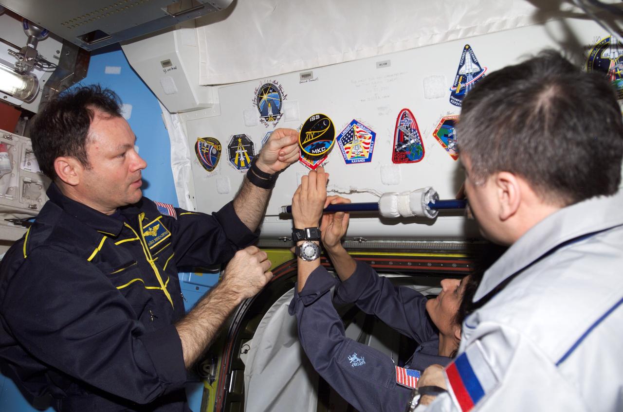 ISS014-E-19558 (17 April 2007) --- Astronauts Michael E. Lopez-Alegria (left), Expedition 14 commander and NASA space station science officer; Sunita L. Williams, flight engineer; and cosmonaut Mikhail Tyurin, flight engineer representing Russia's Federal Space Agency, adds the Expedition 14 patch to the growing collection of insignias representing crews who have performed spacewalks from the Quest Airlock of the International Space Station.