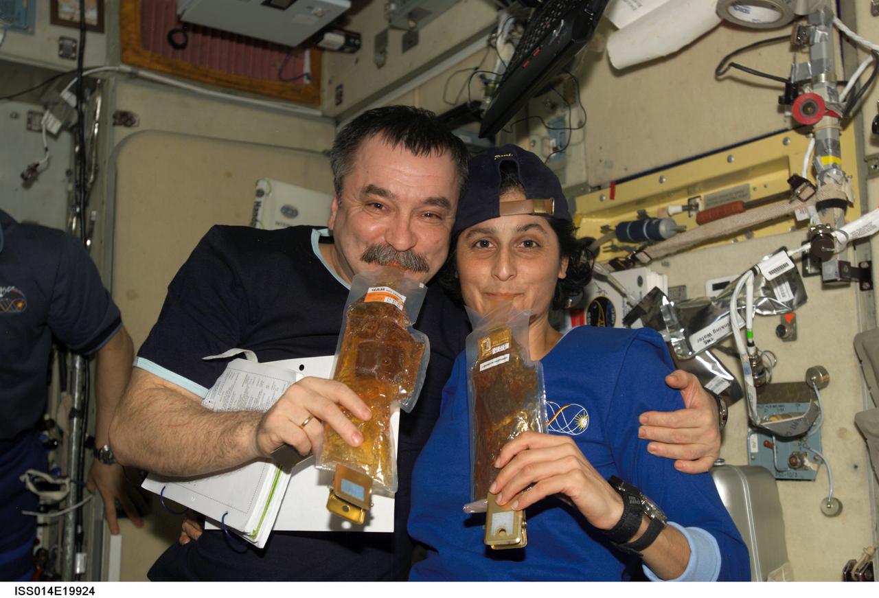 ISS014-E-19924 (21 April 2007) --- Cosmonaut Mikhail Tyurin (left), Expedition 14 flight engineer representing Russia's Federal Space Agency, and astronaut Sunita L. Williams, Expedition 15 flight engineer, drink beverages as they pose for a photo in the Zvezda Service Module of the International Space Station.