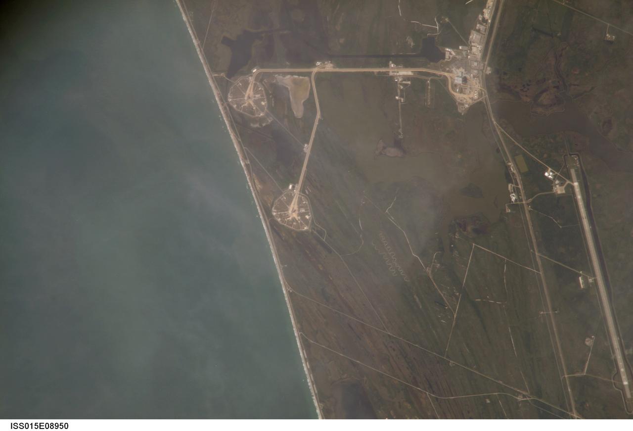ISS015-E-08950 (21 May 2007) --- An 800-mm lens look from the International Space Station shows the Kennedy Space Center around midday on May 21, 2007.  Astronaut Sunita L. Williams, Expedition 15 flight engineer, took the photo. The Space Shuttle Atlantis, scheduled for a launch no earlier than June 8, sits on Pad A (near top center frame) at launch complex 39. Pad B can be seen near center frame.  The giant Vehicle Assembly Building (upper right) and part of the Shuttle Landing Facility (near lower right edge) are among other facilities seen in the digital frame.