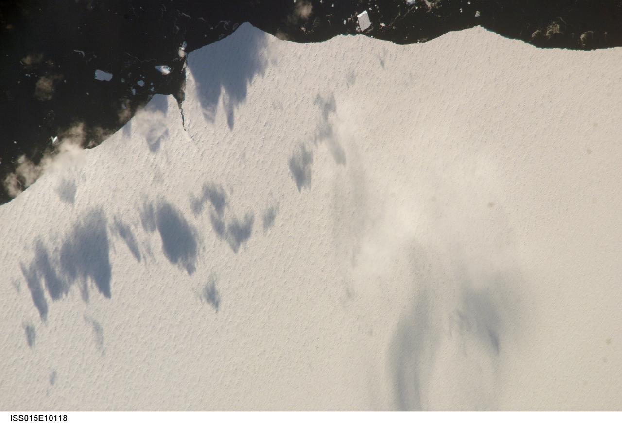 ISS015-E-10118 (30 May 2007) --- A close-up view of an area of an iceberg in the South Atlantic Ocean is featured in this image photographed by an Expedition 15 crewmember on the International Space Station. This iceberg illustrates the remains of a giant iceberg -- designated A22A that broke off Antarctica in 2002. This is one of the largest icebergs to drift as far north as 50 degrees south latitude, bringing it beneath the daylight path of the station. Crewmembers aboard the orbital complex were able to locate the ice mass and photograph it, despite great cloud masses of winter storms in the Southern Ocean. Dimensions of A22A in early June were 49.9 x 23.4 kilometers, giving it an area of 622 square kilometers, or seven times the area of Manhattan Island. Once the station crew had located the iceberg, they managed to image it successfully with the "long" 800-mm lens. Handling the longer lens requires practice: with the speed of movement of the spacecraft and the length of the lens, it is necessary to "track" the target, which is, swinging the camera slowly to keep the target in the middle of the view finder. If you track too slowly or too fast, the image looks smeared. As in this image, the long lens only shows a small part of the iceberg. A series of parallel lines, termed "hummocks", can be seen. These hummocks are probably dunes of snow that have become solidified, and date back to the time when the iceberg was connected to Antarctica. A developing fracture in the ice is also visible at upper left.