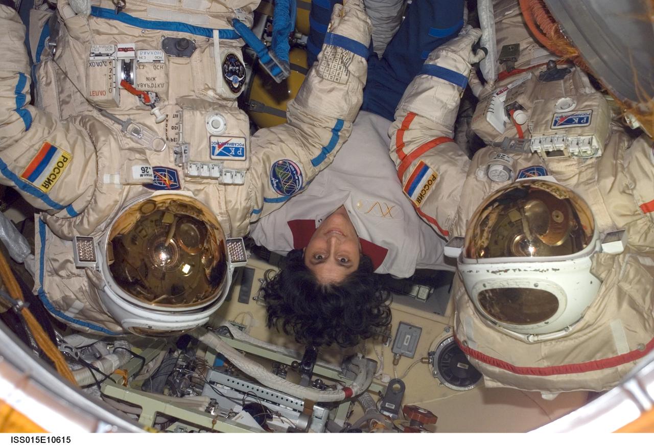 ISS015-E-10615 (3 June 2007) --- Astronaut Sunita L. Williams, Expedition 15 flight engineer, poses for a photo with two Russian Orlan spacesuits in the Pirs Docking Compartment of the International Space Station.