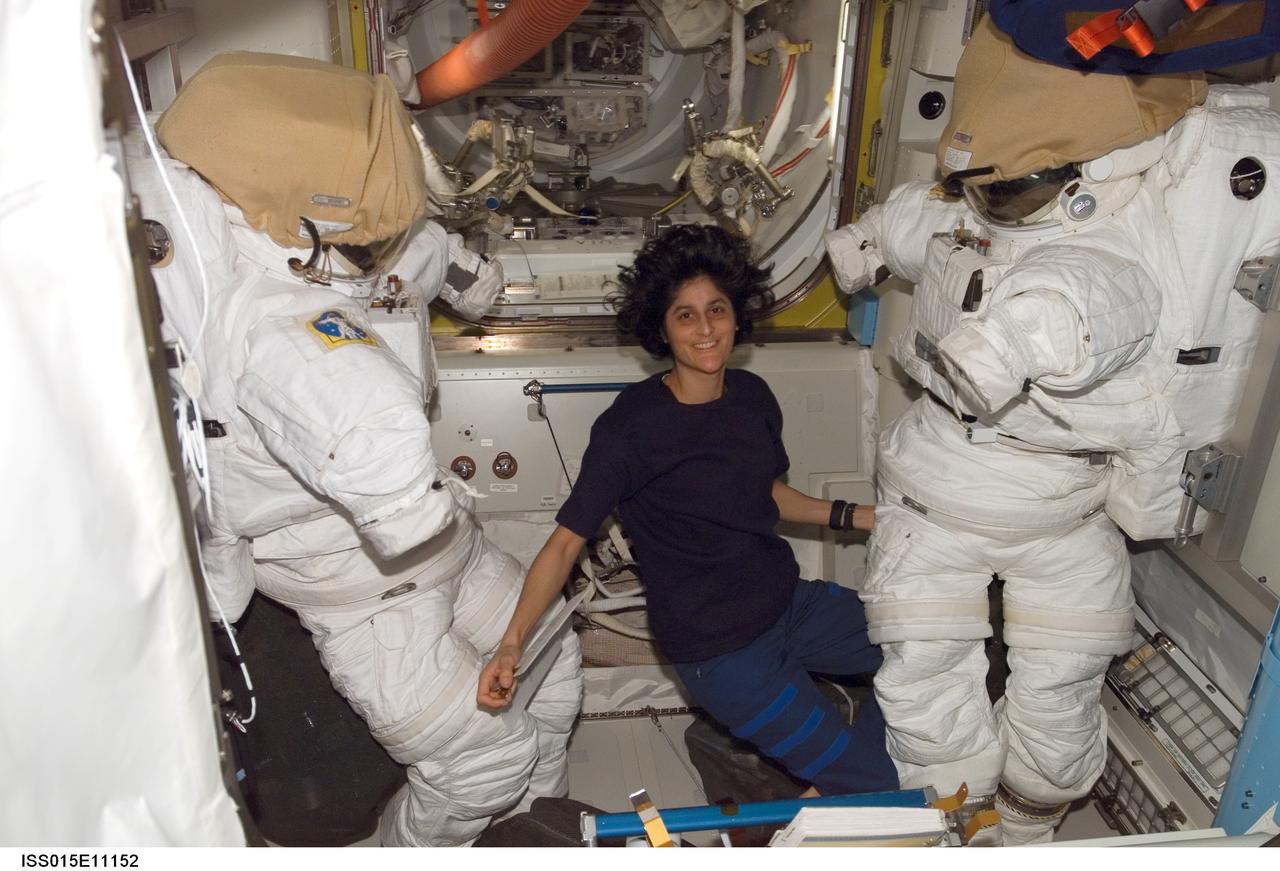 ISS015-E-11152 (7 June 2007) --- Astronaut Sunita L. Williams, Expedition 15 flight engineer, poses with two Extravehicular Mobility Unit (EMU) spacesuits in the Quest Airlock of the International Space Station.