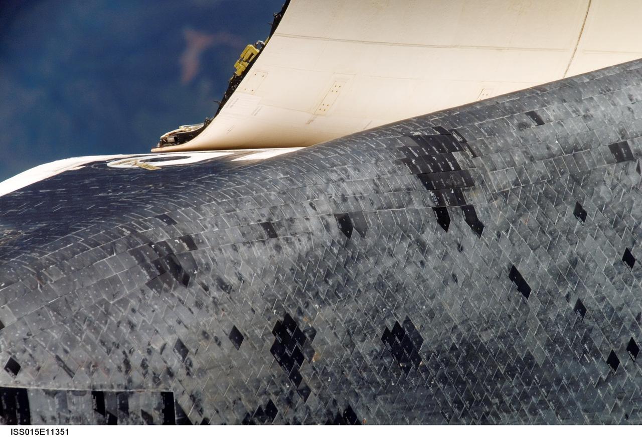 ISS015-E-11351 (10 June 2007) --- This is one of a series of images photographed with a digital still camera using an 800mm focal length featuring the different areas of the Space Shuttle Atlantis as it approached the International Space Station and performed a back-flip to accommodate close scrutiny by eyeballs and cameras.  This image shows part of Atlantis' underside thermal protection system and part of the port side cabin, including the hatch, as well as a section of the open payload bay cover. Distance from the station and shuttle at this time was approximately 600 feet.