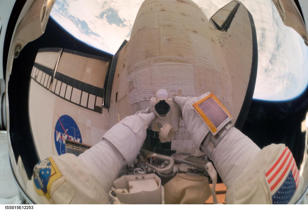 ISS015-E-12253 (15 June 2007) --- The helmet visor of astronaut John "Danny" Olivas, STS-117 mission specialist, serves as an easel of sorts as it reflects a pictorial account of a portion of a very busy session of extravehicular activity (EVA) on June 15. Olivas, who took the photo, spent two hours of an overall 7 hour, 58 minute spacewalk stapling and pinning down a piece of thermal blanket on one of Atlantis' orbital maneuvering system pods (reflected in his visor).  The 4-by-6-inch corner of the blanket peeled up during the shuttle's launch last week.