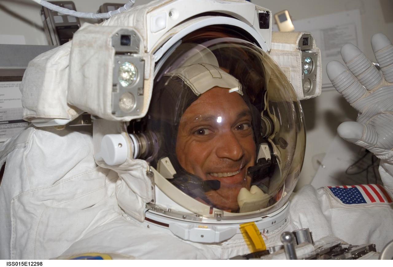 ISS015-E-12298 (15 June 2007) --- Attired in his Extravehicular Mobility Unit (EMU) spacesuit, astronaut John "Danny" Olivas, STS-117 mission specialist, waves as he awaits the start of the mission's third session of extravehicular activity (EVA) in the Quest Airlock of the International Space Station while Space Shuttle Atlantis was docked with the station.