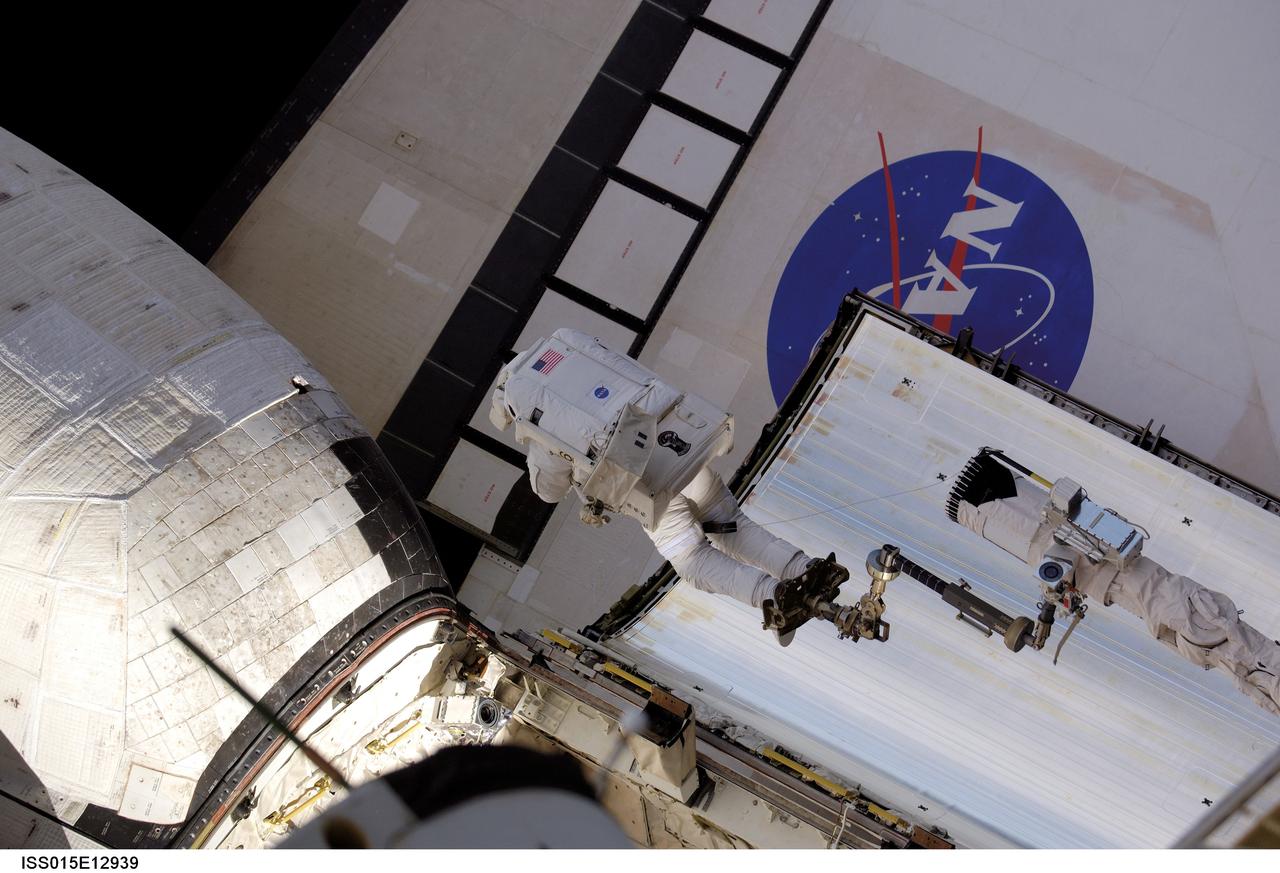 ISS015-E-12939 (15 June 2007) --- Anchored to a foot restraint on Space Shuttle Atlantis' remote manipulator system (RMS) robotic arm, astronaut John "Danny" Olivas, STS-117 mission specialist, moves toward Atlantis' port orbital maneuvering system (OMS) pod that was damaged during the shuttle's climb to orbit last week. During the repair, Olivas pushed the turned up portion of the thermal blanket back into position, used a medical stapler to secure the layers of the blanket, and pinned it in place against adjacent thermal tile.