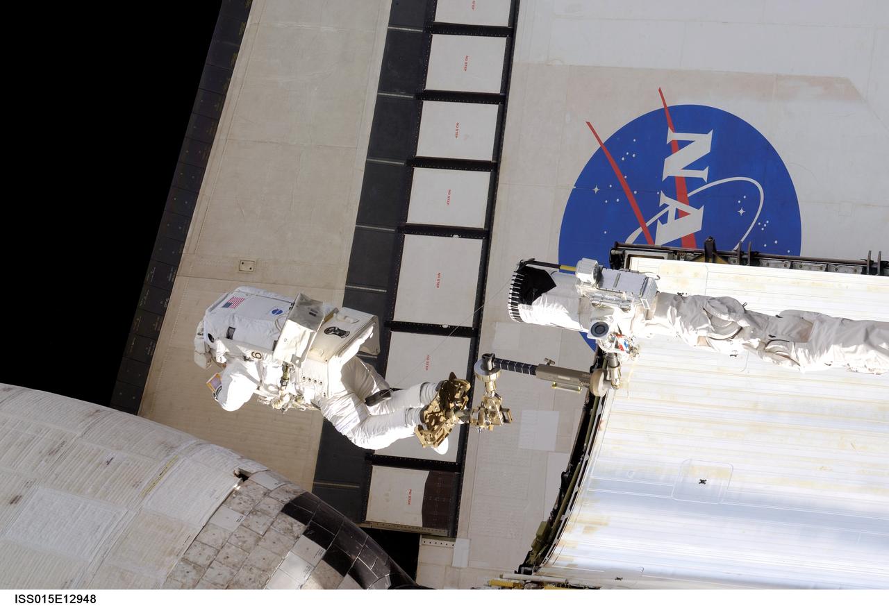 ISS015-E-12948 (15 June 2007) --- Anchored to a foot restraint on Space Shuttle Atlantis' remote manipulator system (RMS) robotic arm, astronaut John "Danny" Olivas, STS-117 mission specialist, moves toward Atlantis' port orbital maneuvering system (OMS) pod that was damaged during the shuttle's climb to orbit last week. During the repair, Olivas pushed the turned up portion of the thermal blanket back into position, used a medical stapler to secure the layers of the blanket, and pinned it in place against adjacent thermal tile.