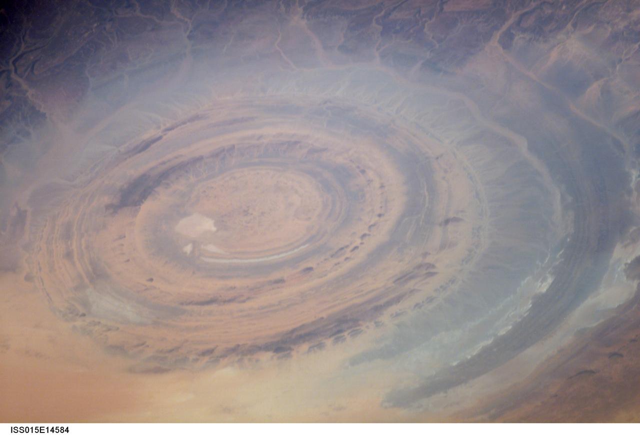 ISS015-E-14584 (26 June 2007) --- The "bull's-eye" of the Richat Structure in the barren Gres de Chinguetti Plateau, central Mauritania in northwest Africa is featured in this image photographed by an Expedition 15 crewmember on the International Space Station. It represents domally uplifted, layered (sedimentary) rocks that have been eroded by water and wind into the present shape. The 25-mile-wide structure is a 300-foot-deep landmark that has caught the eye of many an astronaut in Earth orbit.