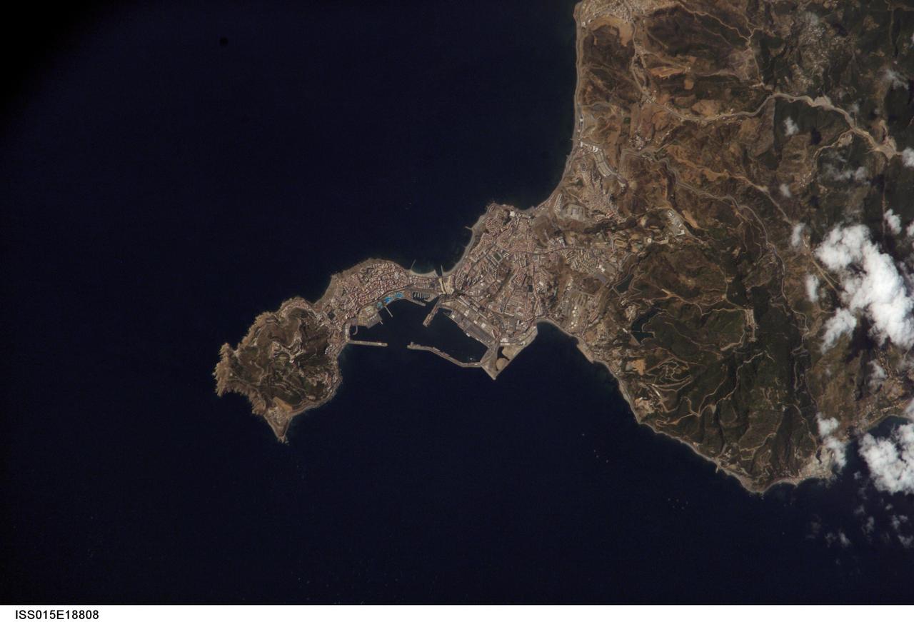 ISS015-E-18808 (21 July 2007) --- Ceuta on the northern African coastline is featured in this image photographed by an Expedition 15 crewmember on the International Space Station. The small Spanish enclave of Ceuta occupies a narrow isthmus of land on the African side of the Strait of Gibraltar. This view illustrates the sharp contrast in land cover between urban Ceuta (pink to white residential and industrial rooftops at center), the bay formed by seawalls to the north of the city, and the higher elevations of Monte Hacho forming the end of the isthmus. Green, vegetated slopes surround the Spanish fort atop the mountain, which commands a clear view of the Strait of Gibraltar to the northwest (not shown).  Several small dots are visible near the coastline to the northwest and south of Ceuta -- these are small pleasure or fishing boats.