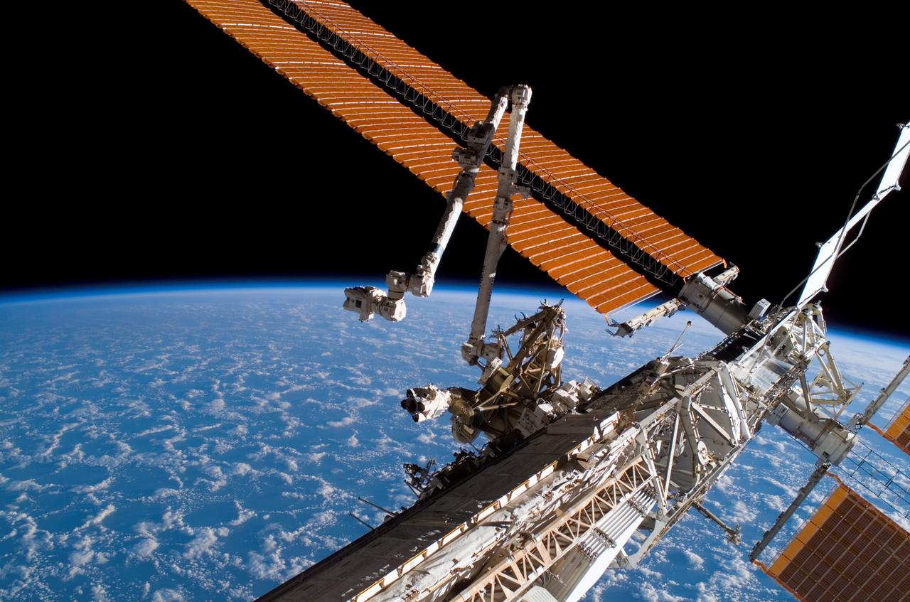 ISS015-E-21945 (11 Aug. 2007) --- The Canadarm2 (center) and solar array panel wings on the International Space Station are featured in this image photographed by a crewmember during the mission's first planned session of extravehicular activity (EVA) while Space Shuttle Endeavour (STS-118) was docked with the station. The blackness of space and Earth's horizon provide the backdrop for the scene.