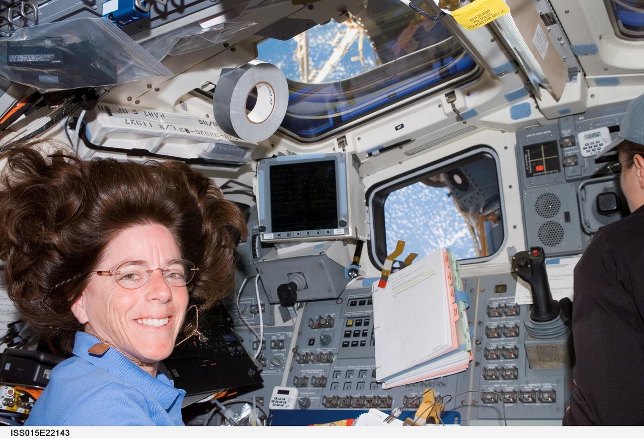 ISS015-E-22143 (12 Aug. 2007) --- Astronaut Barbara R. Morgan, STS-118 mission specialist, pauses for a photo while working the controls on the aft flight deck of Space Shuttle Endeavour while docked with the International Space Station. Astronaut Tracy Caldwell (partially out of fame), mission specialist, is visible at right.