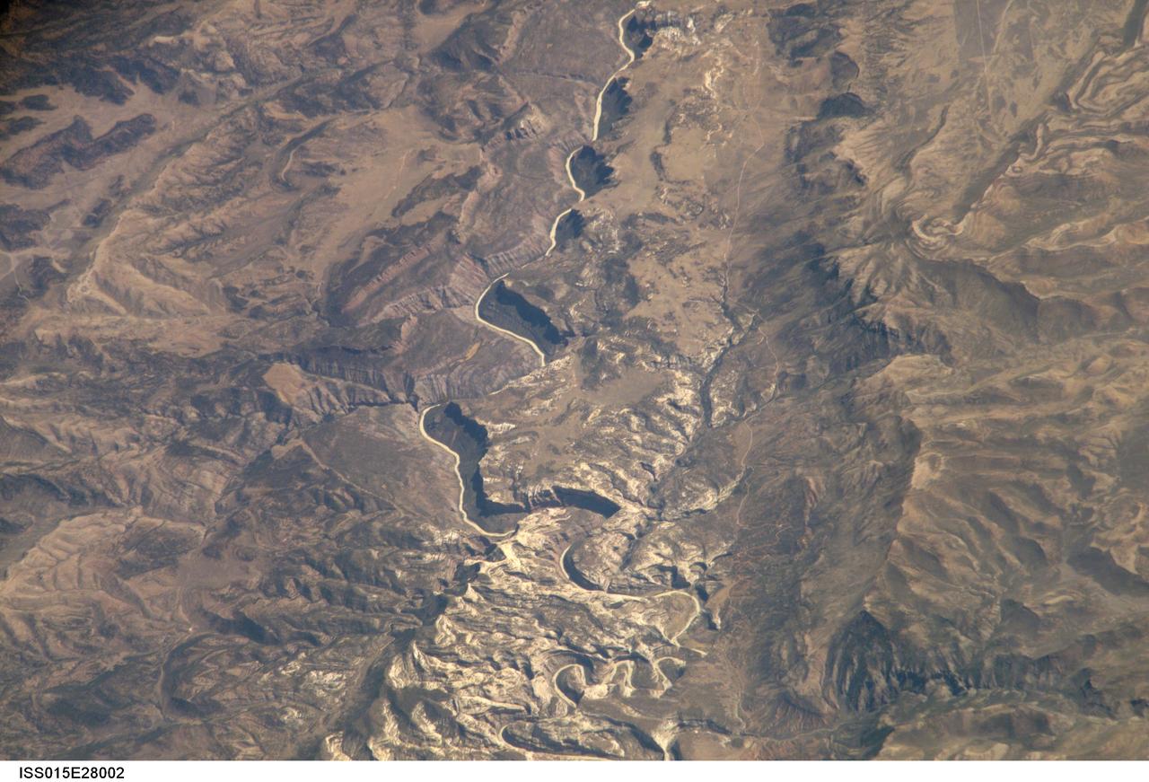 ISS015-E-28002 (12 Sept. 2007) --- A section of Dinosaur National Monument along the Yampa River in Colorado, which straddles the Colorado/Utah border, is featured in this image photographed by an Expedition 15 crewmember on the International Space Station. Dinosaur National Monument is perhaps best known for the abundant fossils found in the approximately 145 Ma (mega-annum, or millions of years old) Morrison Formation exposed in valleys and low ridges, according to scientists. The fossil assemblage is a unique record of terrestrial life of the period (dinosaurs, plants, and other animal species). Remains accumulated in streams and shallow lakes and were swiftly buried (and preserved) by sediments associated with those environments. Scientists believe these sediments in turn were lithified over many millions of years as they were buried under younger deposits -- forming the distinctive stratigraphy of the Monument. The generally flat-laying "layer cake" geology of the region -- similar to the Colorado Plateau to the south - is expressed in the image by parallel beds of tan, reddish-brown, and gray-brown sedimentary rocks cut by the Yampa River at the northern end of the Monument (top). Erosion by the Yampa River exposed the Morrison layer and its trove of fossil material. Together with other fossils found in both older and younger rock layers in the area, the Dinosaur National Monument remains an important scientific resource that continues to provide new insights into the geologic history and paleoecology of the region.