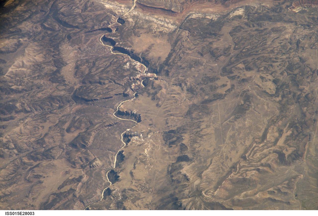 ISS015-E-28003 (12 Sept. 2007) --- A section of Dinosaur National Monument along the Yampa River in Colorado, which straddles the Colorado/Utah border, is featured in this image photographed by an Expedition 15 crewmember on the International Space Station. Dinosaur National Monument is perhaps best known for the abundant fossils found in the approximately 145 Ma (mega-annum, or millions of years old) Morrison Formation exposed in valleys and low ridges, according to scientists. The fossil assemblage is a unique record of terrestrial life of the period (dinosaurs, plants, and other animal species). Remains accumulated in streams and shallow lakes and were swiftly buried (and preserved) by sediments associated with those environments. Scientists believe these sediments in turn were lithified over many millions of years as they were buried under younger deposits -- forming the distinctive stratigraphy of the Monument. The generally flat-laying "layer cake" geology of the region -- similar to the Colorado Plateau to the south - is expressed in the image by parallel beds of tan, reddish-brown, and gray-brown sedimentary rocks cut by the Yampa River at the northern end of the Monument (top). Erosion by the Yampa River exposed the Morrison layer and its trove of fossil material. Together with other fossils found in both older and younger rock layers in the area, the Dinosaur National Monument remains an important scientific resource that continues to provide new insights into the geologic history and paleoecology of the region.