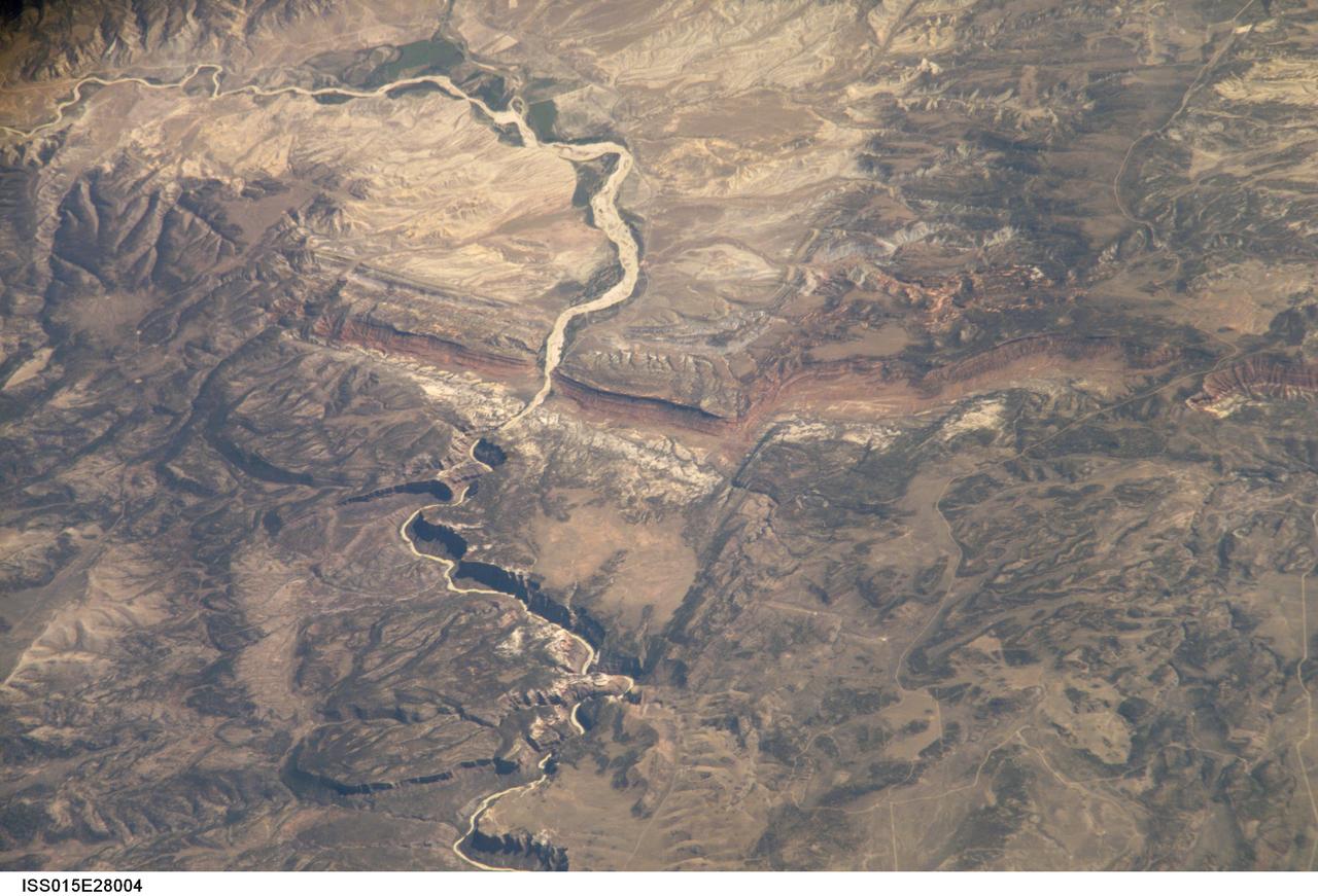 ISS015-E-28004 (12 Sept. 2007) --- A section of Dinosaur National Monument along the Yampa River in Colorado, which straddles the Colorado/Utah border, is featured in this image photographed by an Expedition 15 crewmember on the International Space Station. Dinosaur National Monument is perhaps best known for the abundant fossils found in the approximately 145 Ma (mega-annum, or millions of years old) Morrison Formation exposed in valleys and low ridges, according to scientists. The fossil assemblage is a unique record of terrestrial life of the period (dinosaurs, plants, and other animal species). Remains accumulated in streams and shallow lakes and were swiftly buried (and preserved) by sediments associated with those environments. Scientists believe these sediments in turn were lithified over many millions of years as they were buried under younger deposits -- forming the distinctive stratigraphy of the Monument. The generally flat-laying "layer cake" geology of the region -- similar to the Colorado Plateau to the south - is expressed in the image by parallel beds of tan, reddish-brown, and gray-brown sedimentary rocks cut by the Yampa River at the northern end of the Monument (top). Erosion by the Yampa River exposed the Morrison layer and its trove of fossil material. Together with other fossils found in both older and younger rock layers in the area, the Dinosaur National Monument remains an important scientific resource that continues to provide new insights into the geologic history and paleoecology of the region.