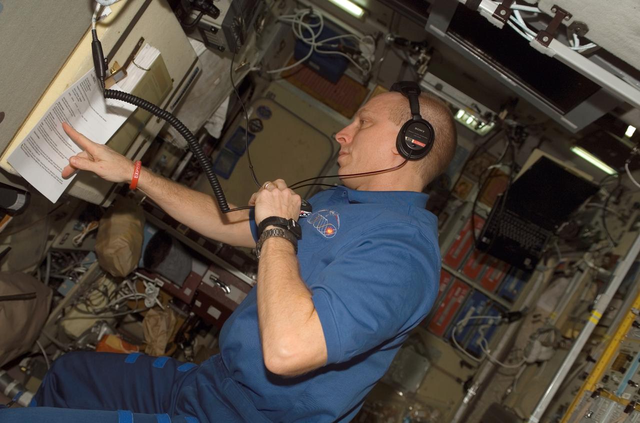 ISS015-E-28715 (14 Sept. 2007) --- Astronaut Clay Anderson, Expedition 15 flight engineer, uses a communication system while checking a procedures checklist in the Zvezda Service Module of the International Space Station.