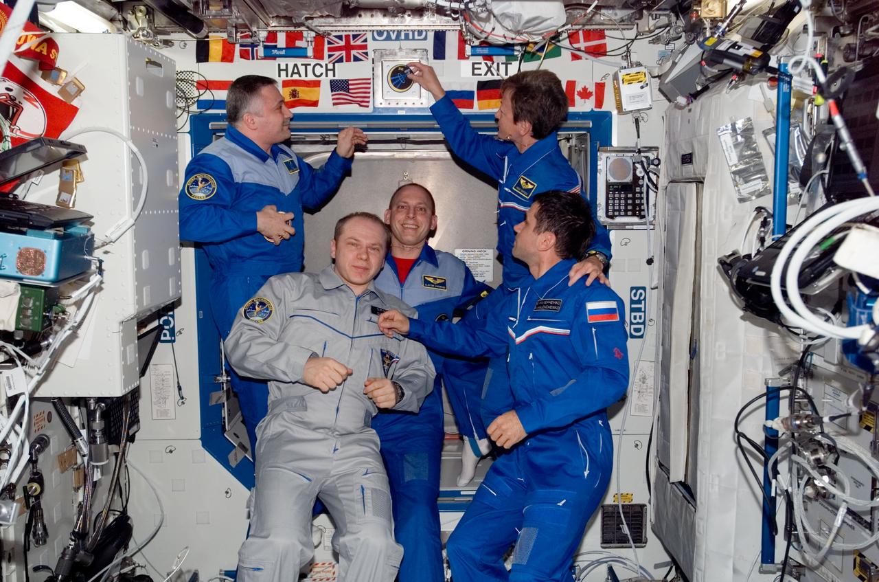 ISS015-E-35320 (19 Oct. 2007) --- NASA astronaut Peggy A. Whitson, Expedition 16 commander, places the Expedition 16 patch above a hatch in the Destiny laboratory, which adds to the growing collection of insignias representing crews who have lived and worked on the International Space Station. Also pictured are cosmonauts Fyodor N. Yurchikhin (left background), Oleg V. Kotov (left foreground), Expedition 15 commander and flight engineer, respectively; and Yuri I. Malenchenko (right), Expedition 16 flight engineer, all representing Russia's Federal Space Agency; and NASA astronaut Clay Anderson, Expedition 15/16 flight engineer.