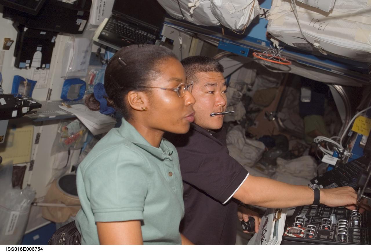 ISS016-E-006754 (26 Oct. 2007) --- Astronauts Stephanie Wilson, STS-120 mission specialist; and Daniel Tani, Expedition 16 flight engineer, work the controls of the Space Station Remote Manipulator System (SSRMS) or Canadarm2 in the Destiny laboratory of the International Space Station while Space Shuttle Discovery is docked with the station.