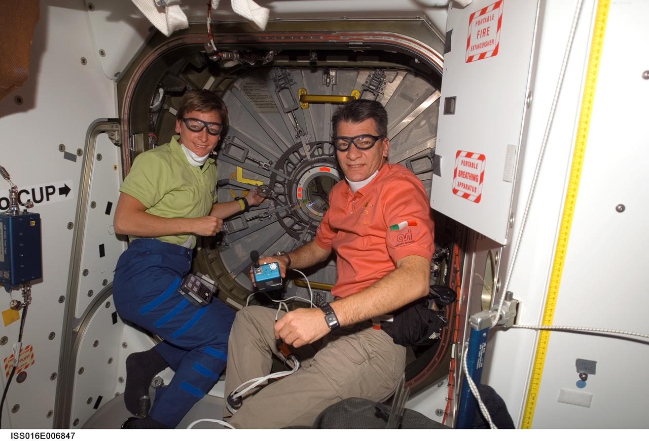 ISS016-E-006847 (27 Oct. 2007) --- NASA astronaut Peggy A. Whitson (left), Expedition 16 commander, and European Space Agency (ESA) astronaut Paolo Nespoli, STS-120 mission specialist, take a moment for a photo as they prepare to open the hatch to the Harmony node -- the newest additional to the International Space Station -- while Space Shuttle Discovery is docked with the station.