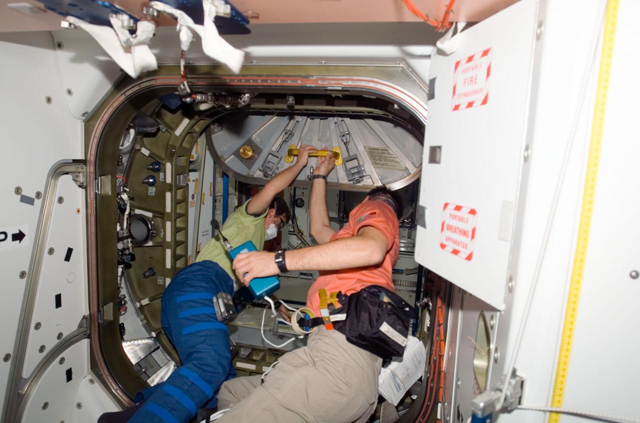 ISS016-E-006856 (27 Oct. 2007) --- NASA astronaut Peggy A. Whitson (left), Expedition 16 commander, and European Space Agency (ESA) astronaut Paolo Nespoli, STS-120 mission specialist, open the hatch to the Harmony node -- the newest additional to the International Space Station -- while Space Shuttle Discovery is docked with the station.
