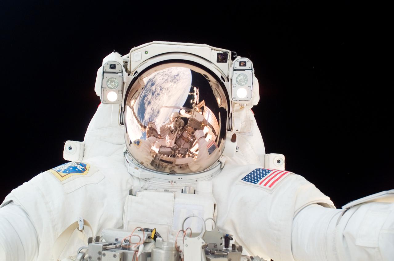 ISS016-E-007421 (30 Oct. 2007) --- Astronaut Scott Parazynski, STS-120 mission specialist, participates in the third scheduled session of extravehicular activity (EVA) as construction continues on the International Space Station. During the 7-hour, 8-minute spacewalk Parazynski and astronaut Doug Wheelock (out of frame), mission specialist, installed the P6 truss segment with its set of solar arrays to its permanent home, installed a spare main bus switching unit on a stowage platform, and performed a few get-ahead tasks. Also, Parazynski inspected the port Solar Alpha Rotary Joint (SARJ) to gather comparison data for the starboard rotary joint. Various components of the station are visible in the reflections in Parazynski's helmet visor.