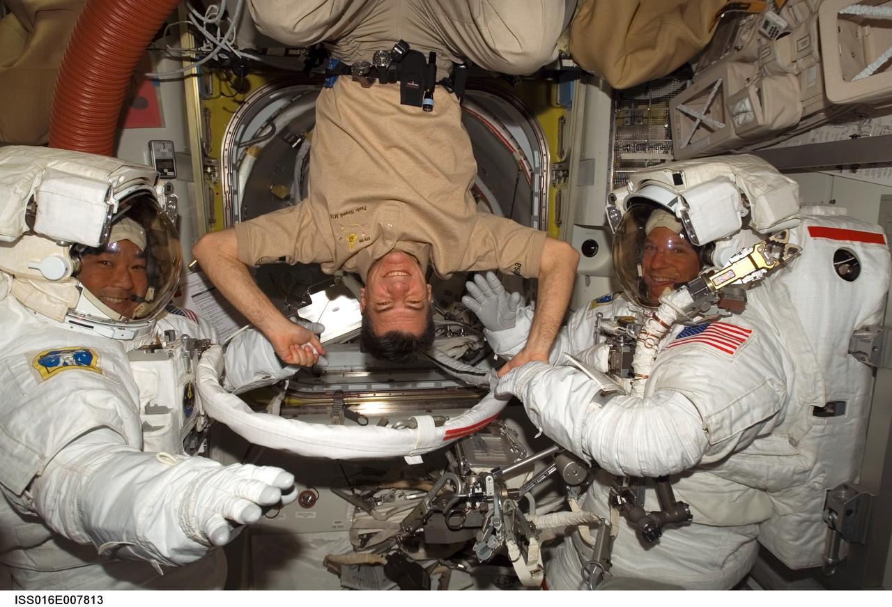 ISS016-E-007813 (28 Oct. 2007) --- European Space Agency (ESA) astronaut Paolo Nespoli (center), STS-120 mission specialist, turns a flip for astronauts Scott Parazynski (right), STS-120 mission specialist, and Daniel Tani, Expedition 16 flight engineer, as they prepare for the mission's second session of extravehicular activity (EVA) in the Quest Airlock of the International Space Station while Space Shuttle Discovery is docked with the station. Parazynski and Tani are attired in their Extravehicular Mobility Unit (EMU) spacesuits.