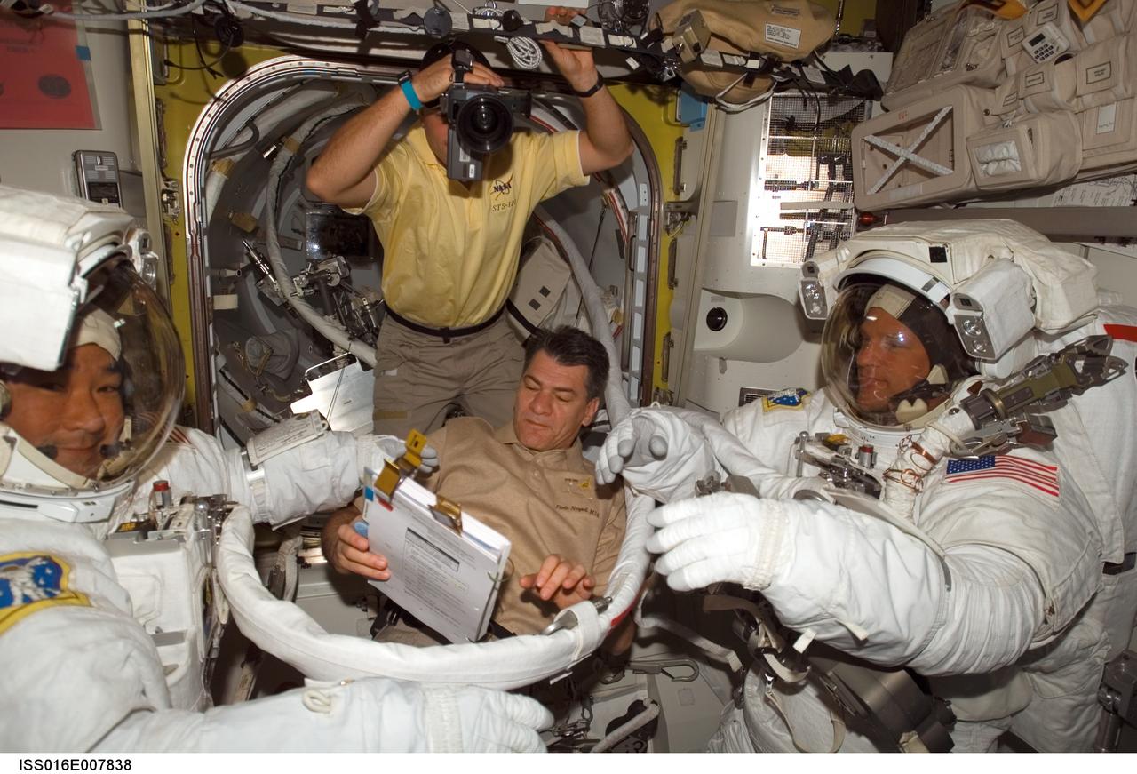 ISS016-E-007838 (28 Oct. 2007) --- Attired in their Extravehicular Mobility Unit (EMU) spacesuits, astronauts Daniel Tani (left), Expedition 16 flight engineer, and Scott Parazynski, STS-120 mission specialist, prepare for the mission's second session of extravehicular activity (EVA) in the Quest Airlock of the International Space Station while Space Shuttle Discovery is docked with the station. European Space Agency (ESA) astronaut Paolo Nespoli (center bottom), STS-120 mission specialist, assisted Tani and Parazynski, while astronaut Doug Wheelock, mission specialist, photographs the event.