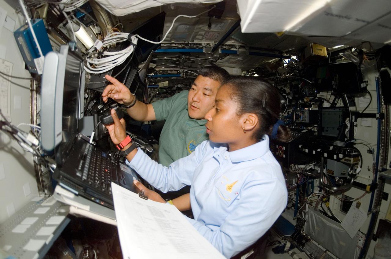 ISS016-E-008075 (30 Oct. 2007) --- Astronauts Stephanie Wilson, STS-120 mission specialist; and Daniel Tani, Expedition 16 flight engineer, work the controls of the Space Station Remote Manipulator System (SSRMS) or Canadarm2 in the Destiny laboratory of the International Space Station while Space Shuttle Discovery is docked with the station.